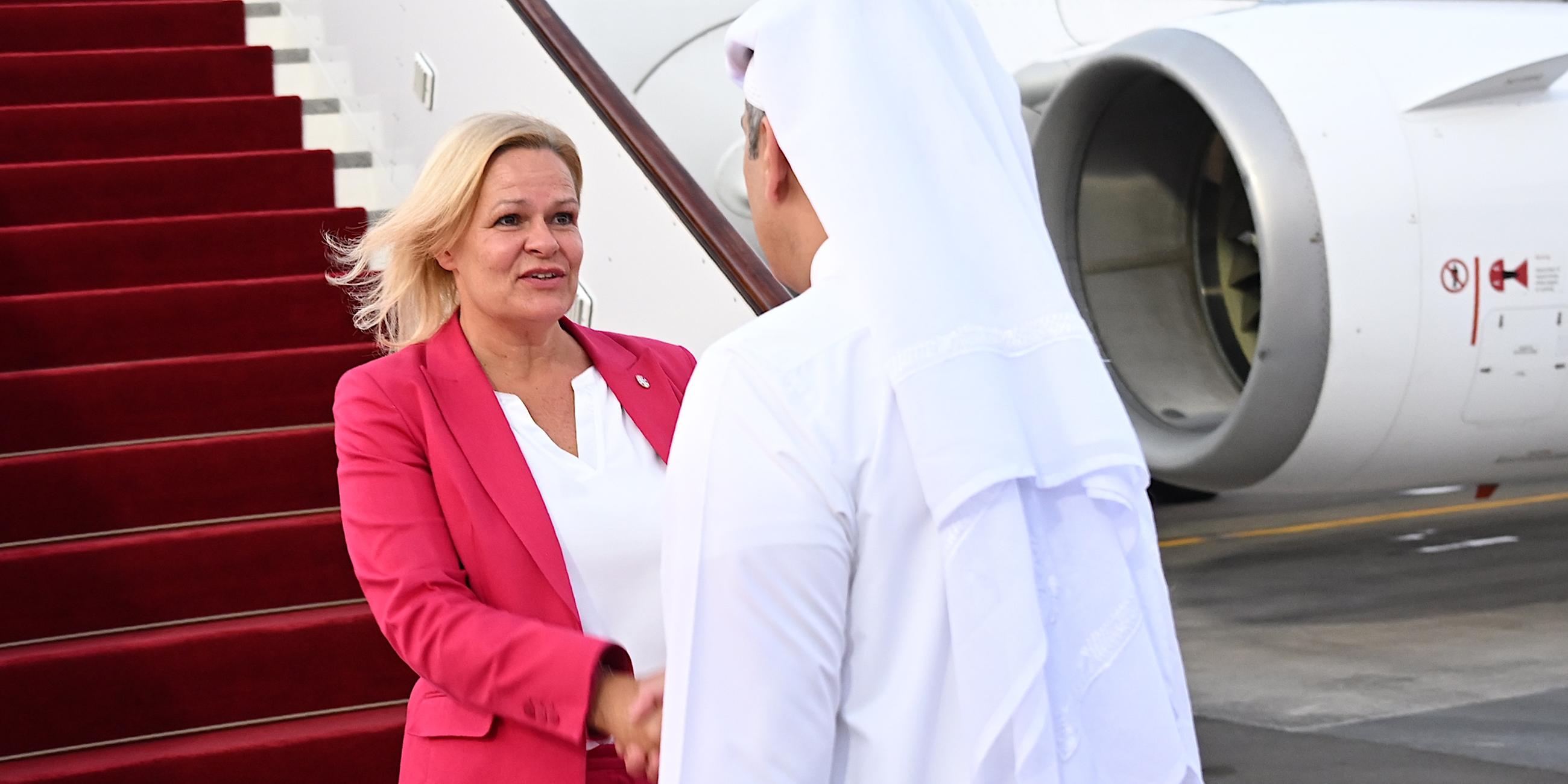 Bundesinnenministerin Nancy Faeser und der Emir von Katar schütteln sich die Hände. Im Hintergrund ein Flugzeug.