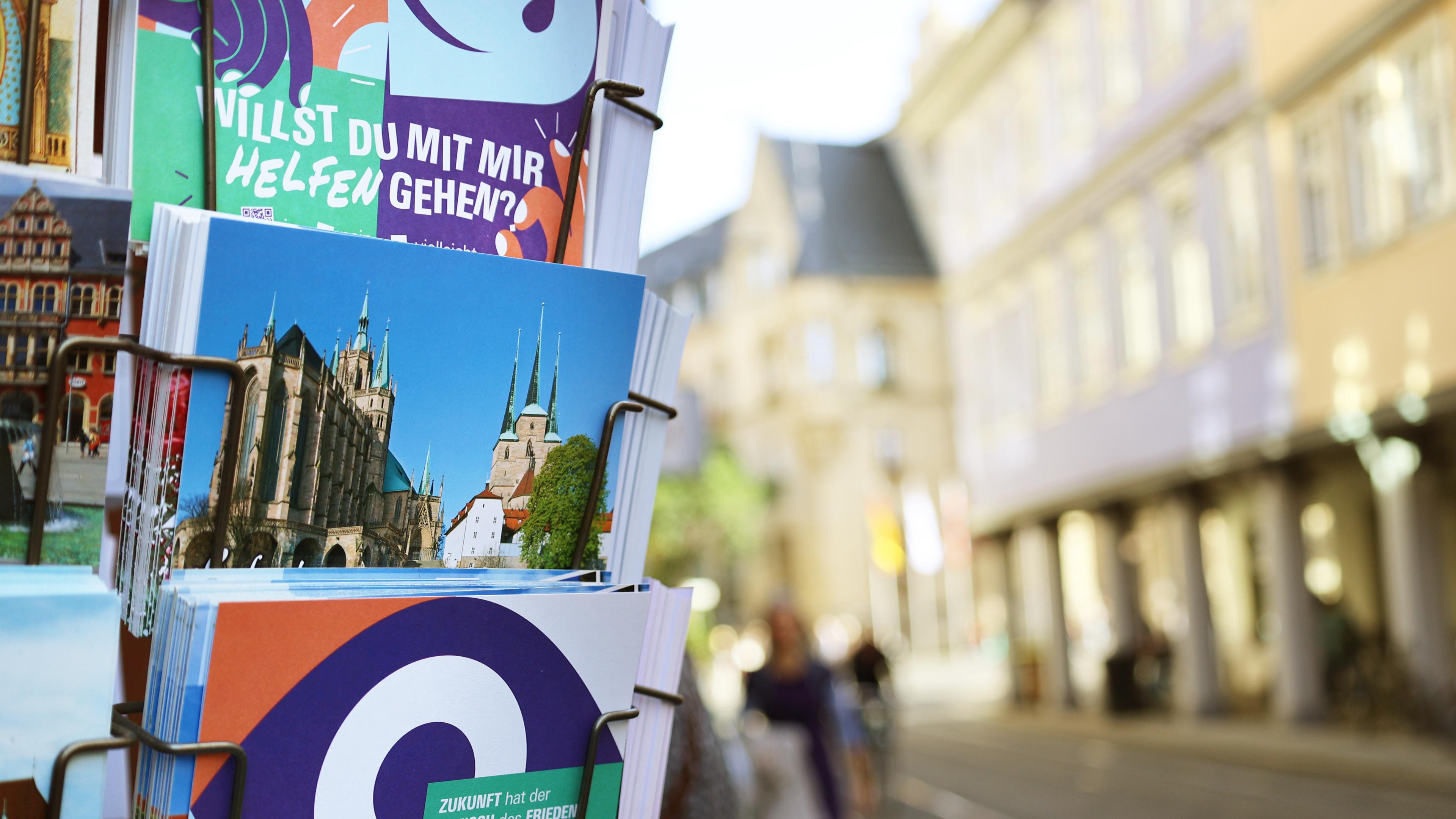 Ein Postkartenständer in Erfurt zeigt u.a. Karten mit dem Text "Willst Du mit mir helfen gehen?"