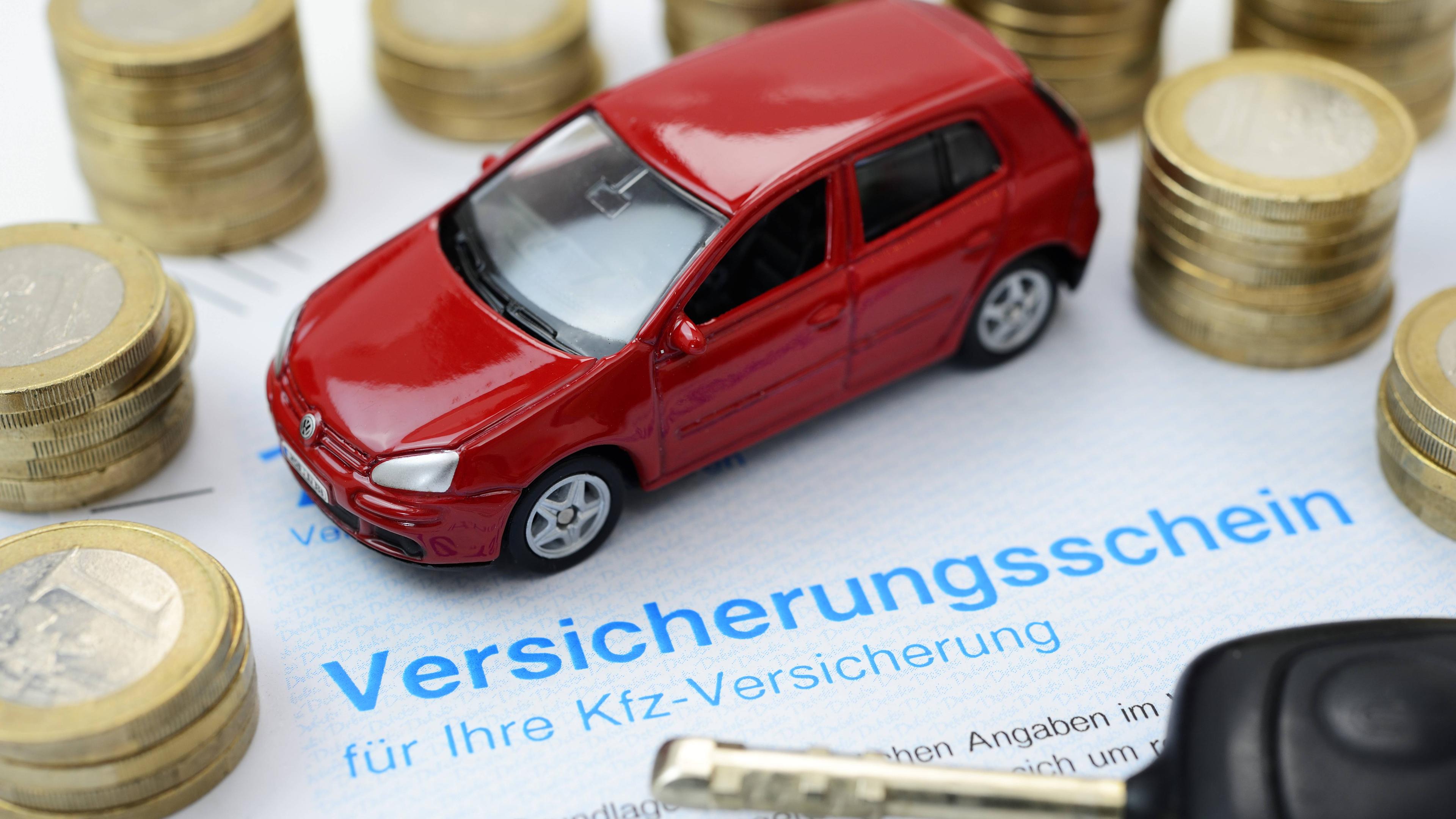 Ein Spielzeug Auto steht auf einem Versicherungsschein