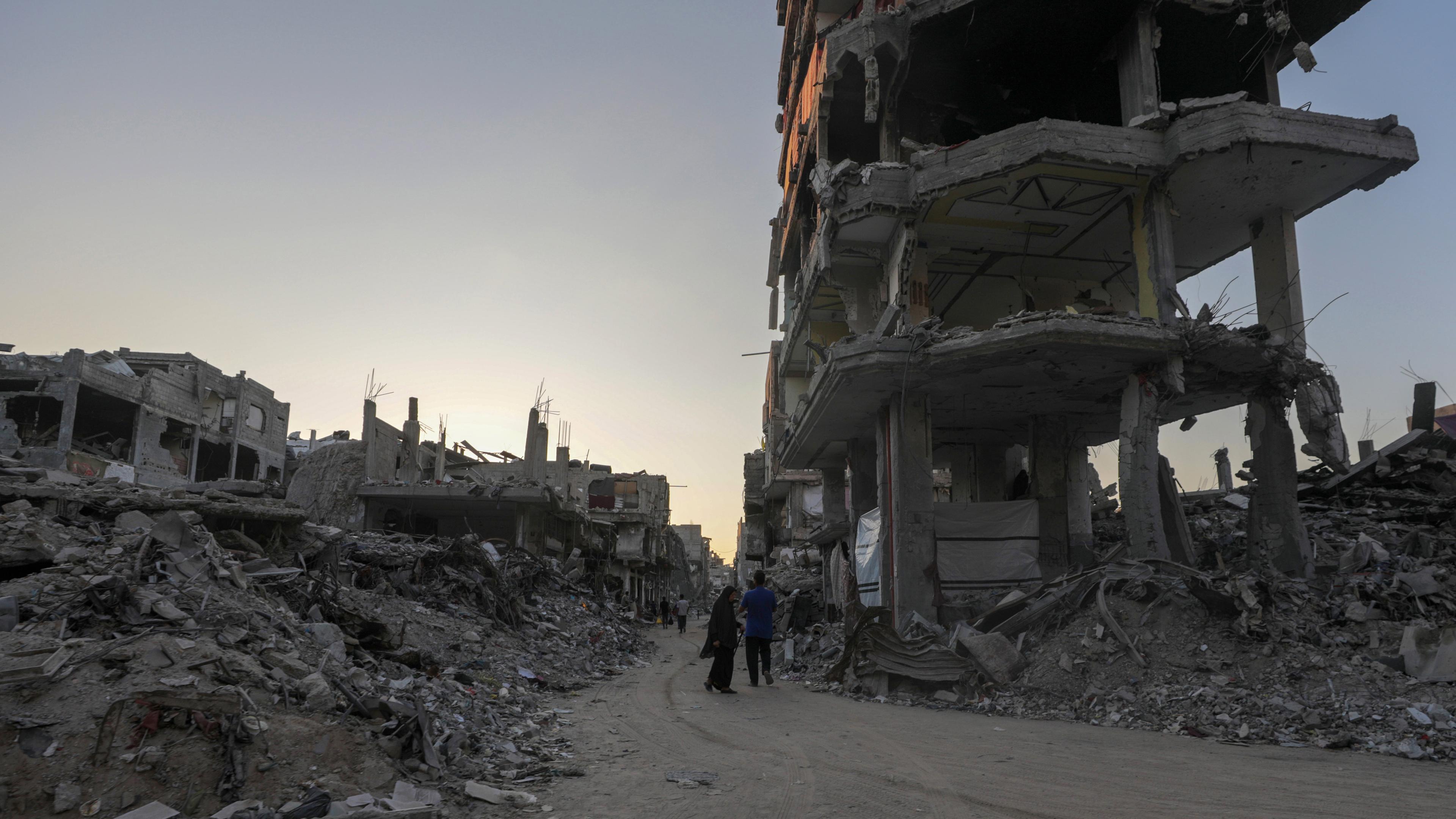 Palästinenser gehen an einem zerstörten Gebäude vorbei durch die Straßen von Khan Younis, südlicher Gazastreifen, 04.08.2024.