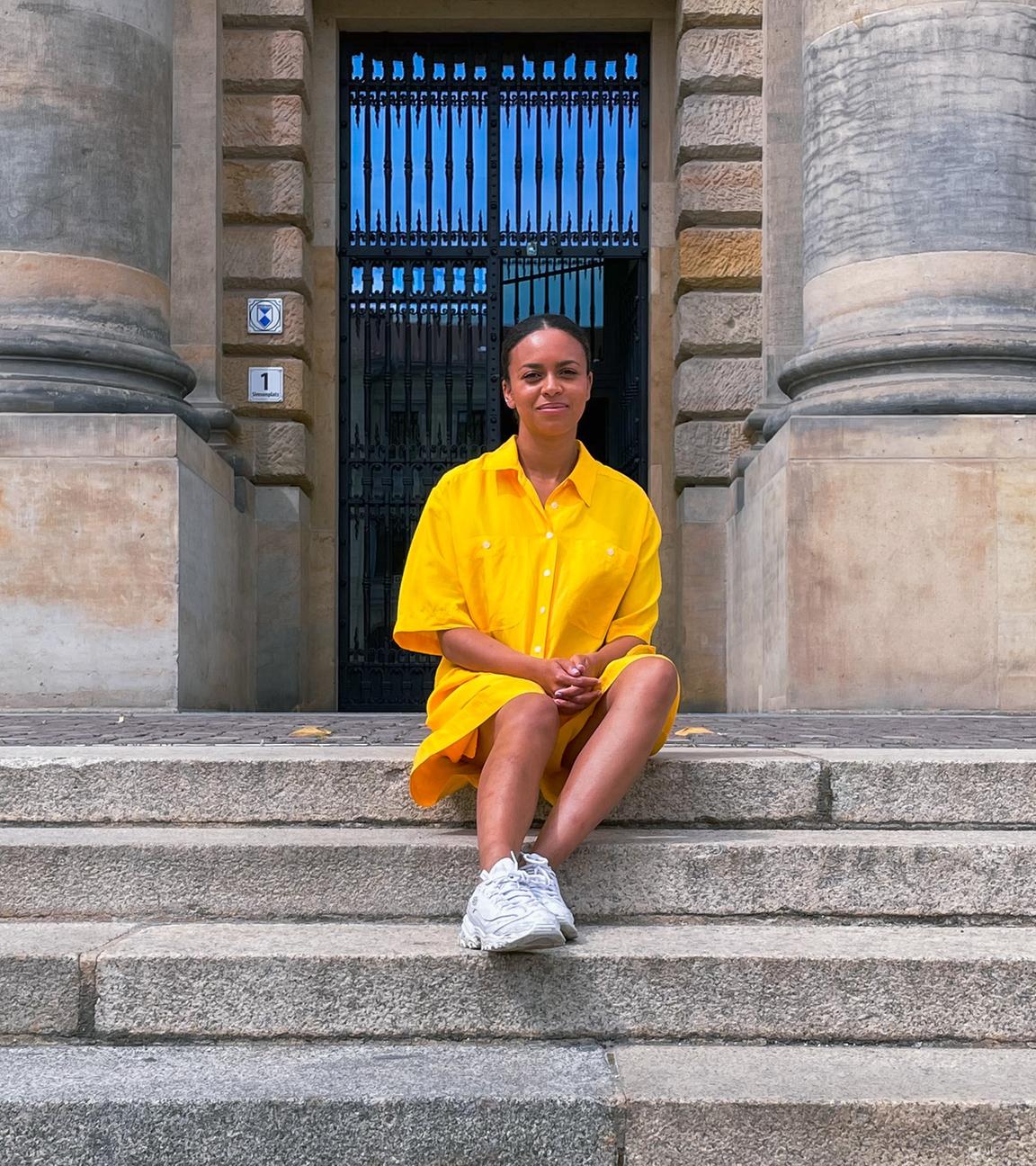 Aminata sitzt auf einer steinernen Treppe. 