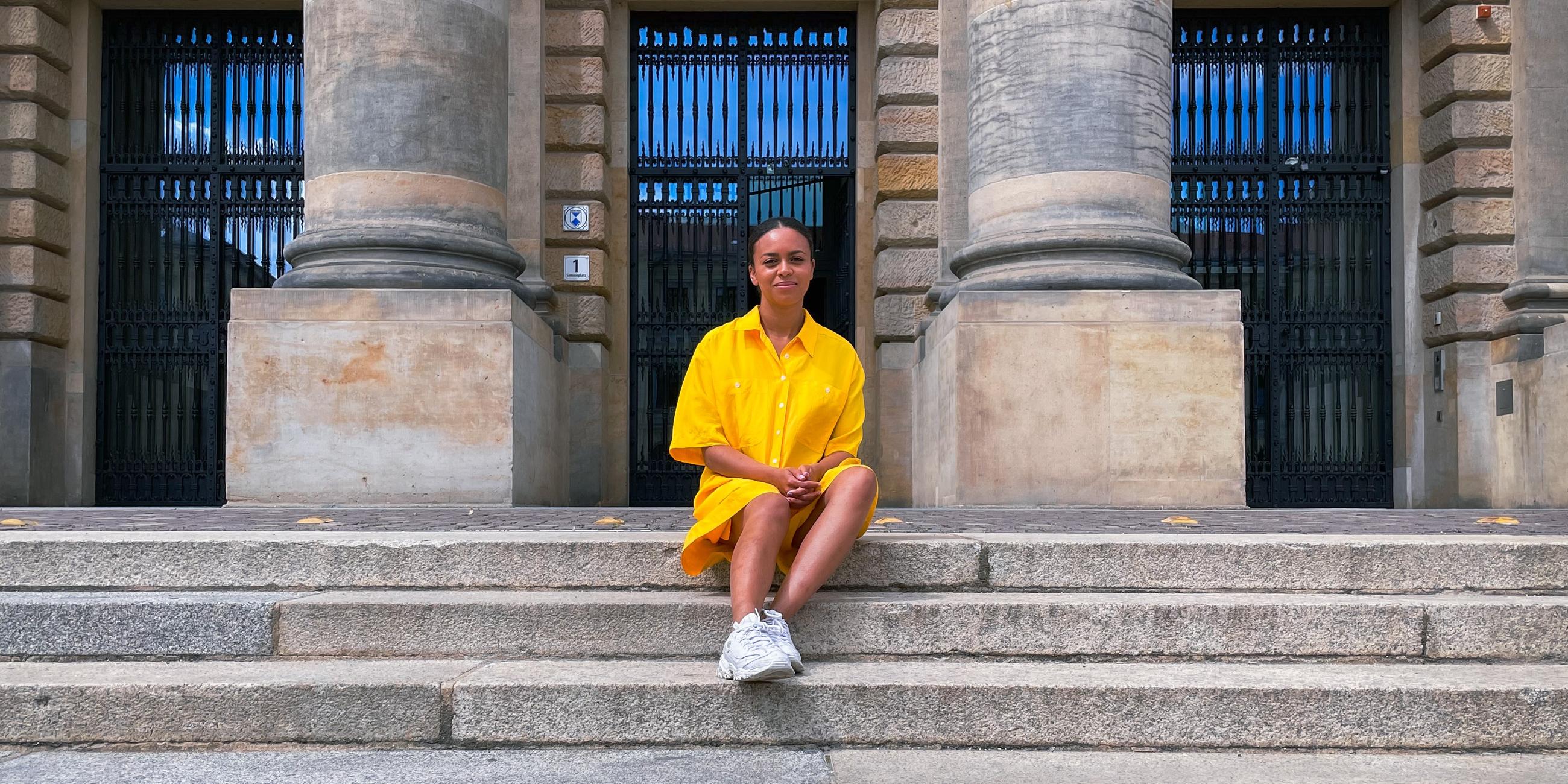 Aminata sitzt auf einer steinernen Treppe. 