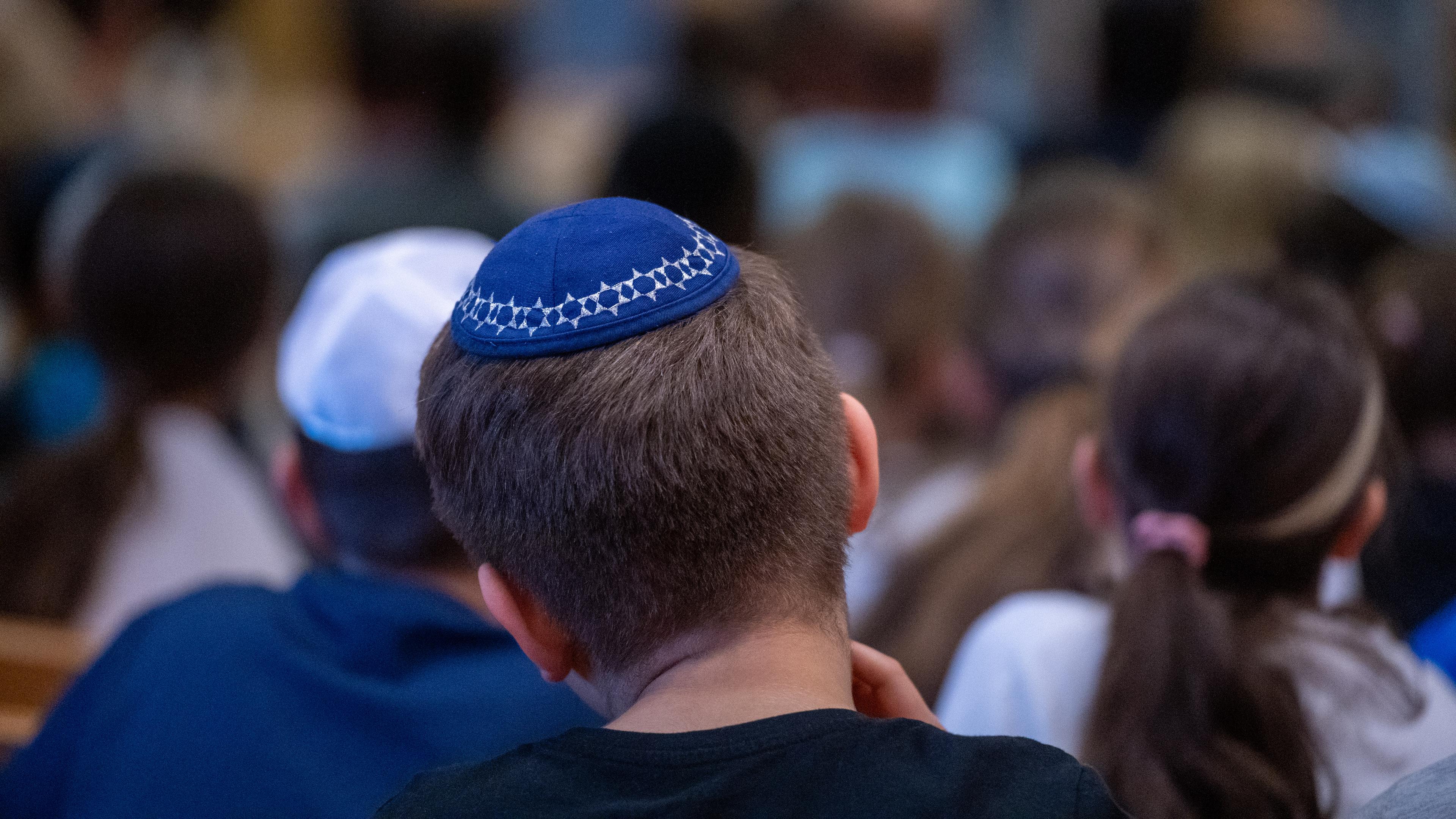 Ein Schüler mit einer Kippa sitzt in der Aula einer Schule. (Archivbild)