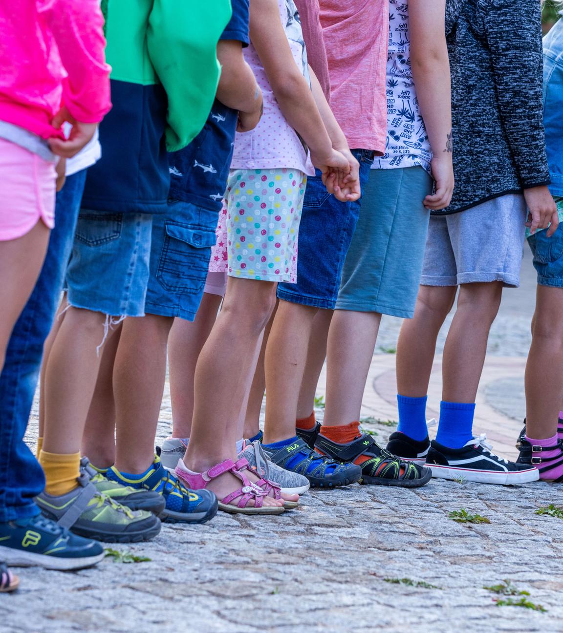 Schüler stehen in einer Reihe auf dem Schulhof einer Grundschule.