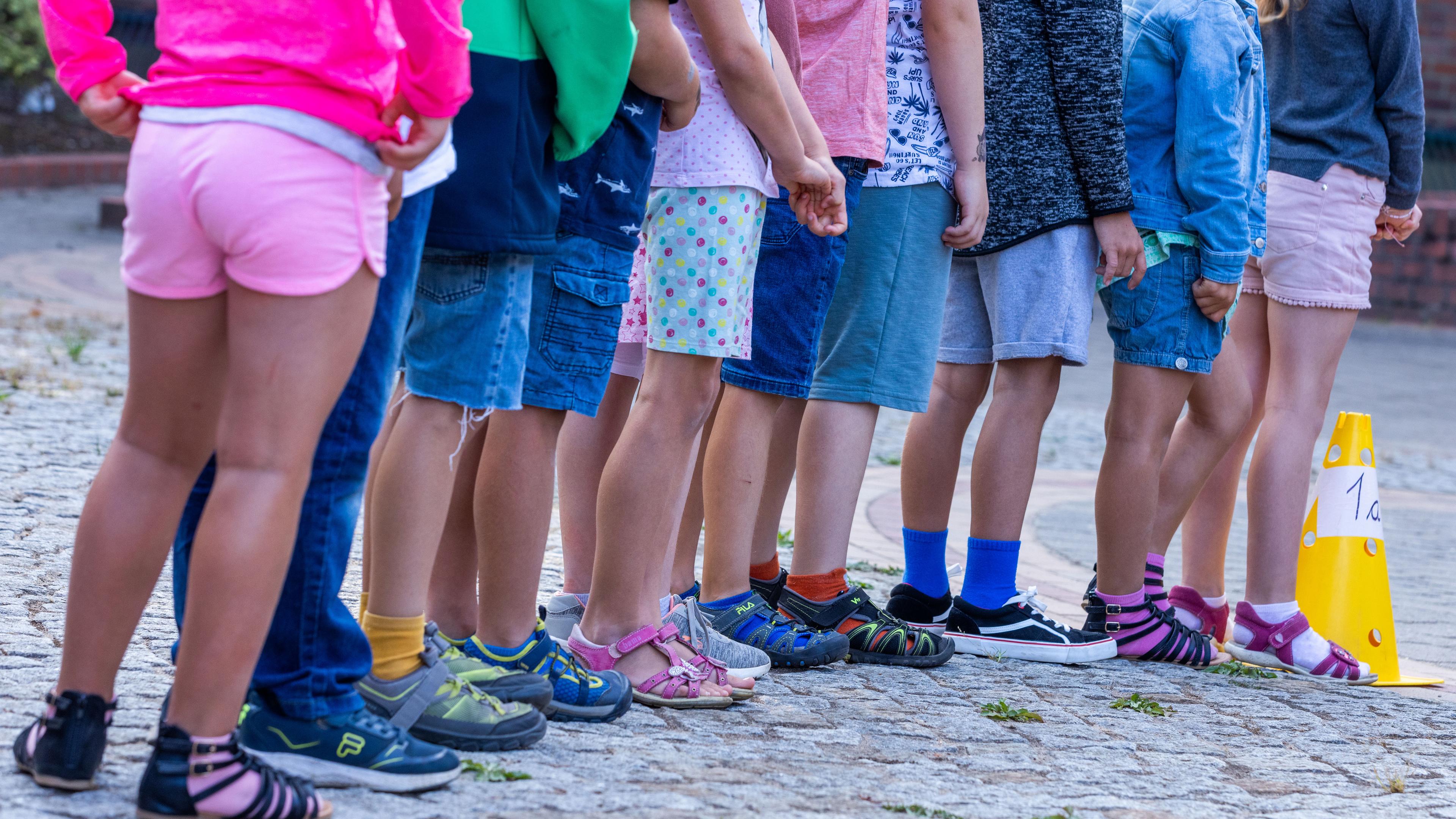 Schüler stehen in einer Reihe auf dem Schulhof einer Grundschule.