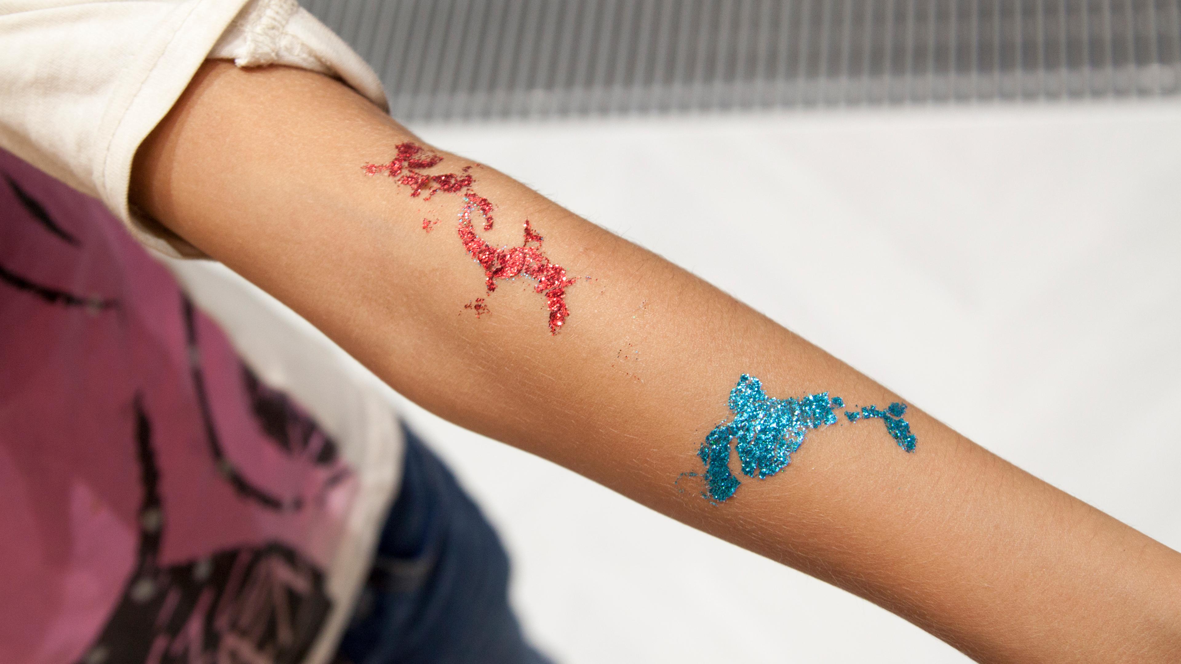 Arm eines Mädchens mit glitzernden temporären Tattoos