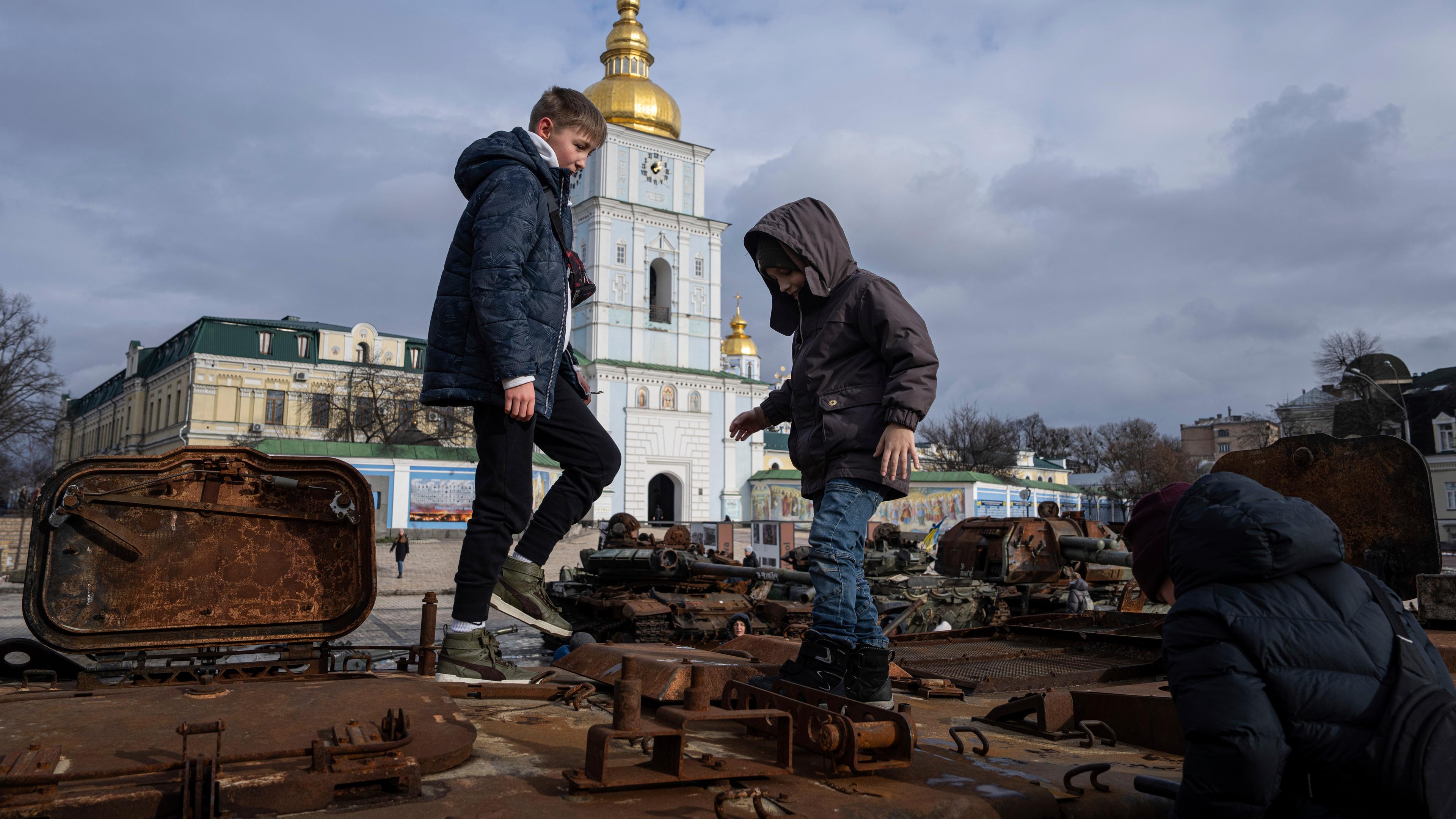 Kinder spielen auf einem zerstörten russischen Fahrzeug in Kiew