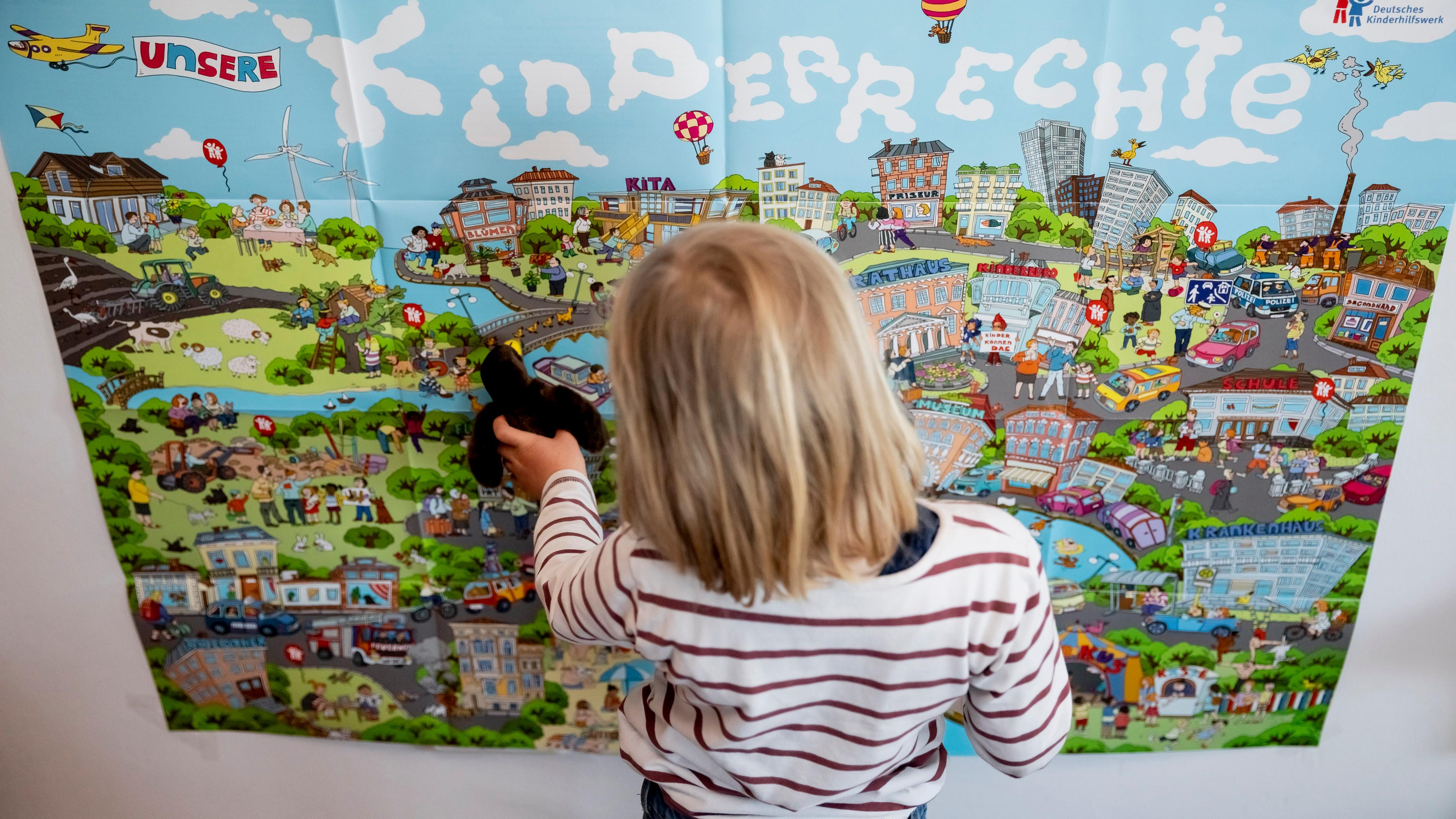 Ein Kind steht vor einem Plakat des Deutschen Kinderhilfswerks mit der Aufschrift «Kinderrechte».