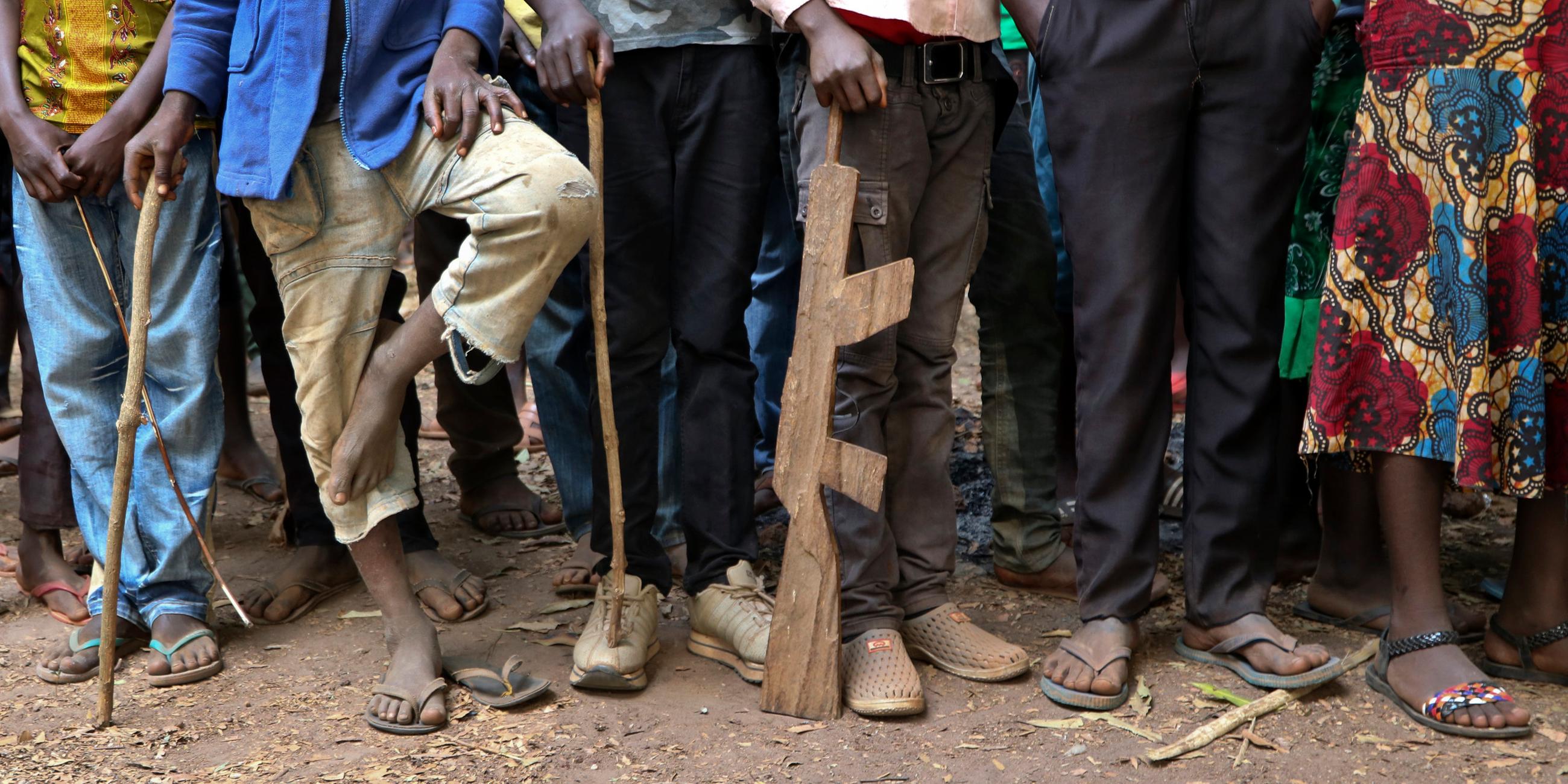 Ehemalige Kindersoldaten warten, um von UNICEF registriert zu werden. Sie haben Waffen aus Holz.