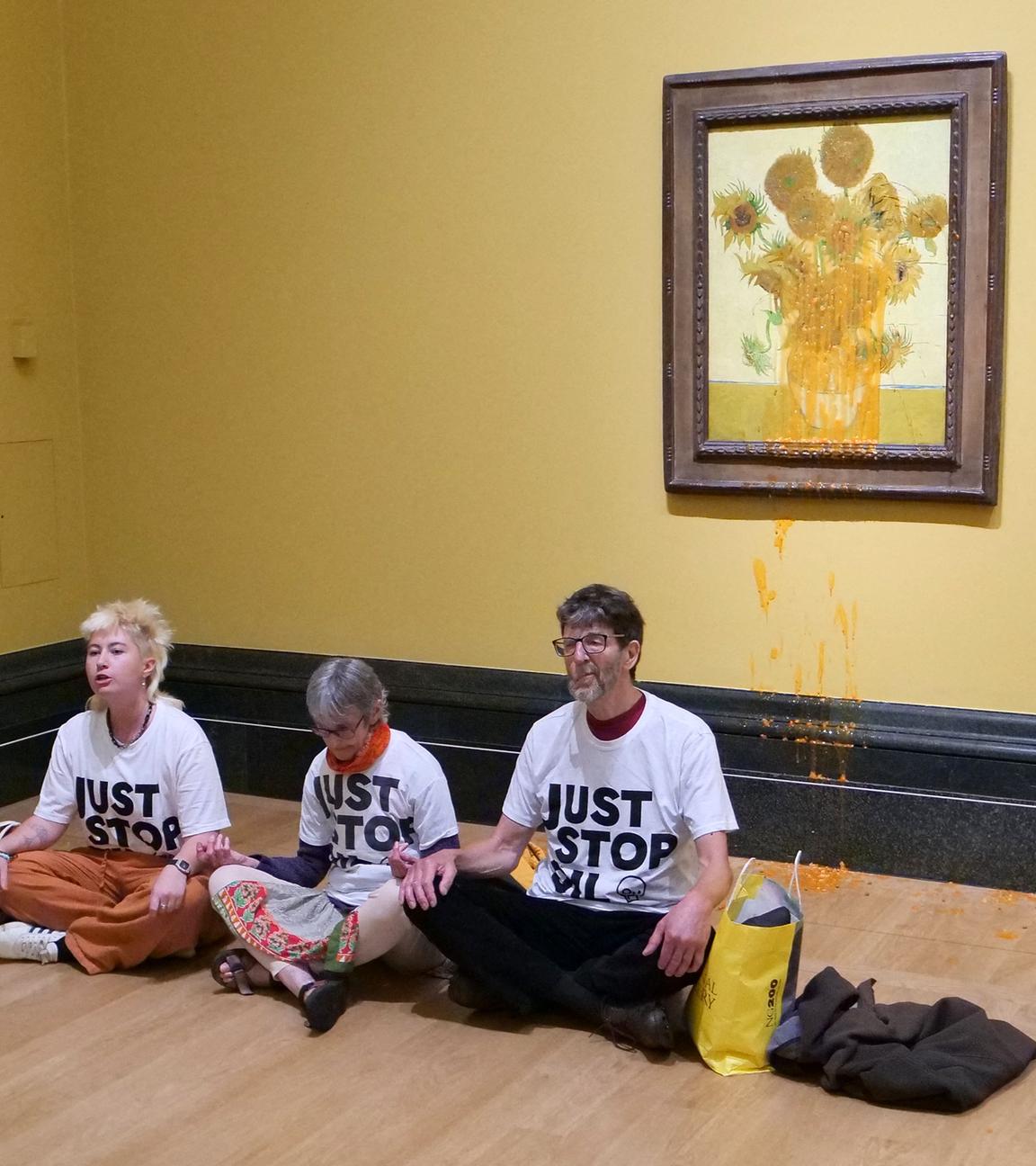 A handout picture from the Just Stop Oil climate campaign group shows three activists sitting on the floor under Vincent van Gogh's "Sunflowers"