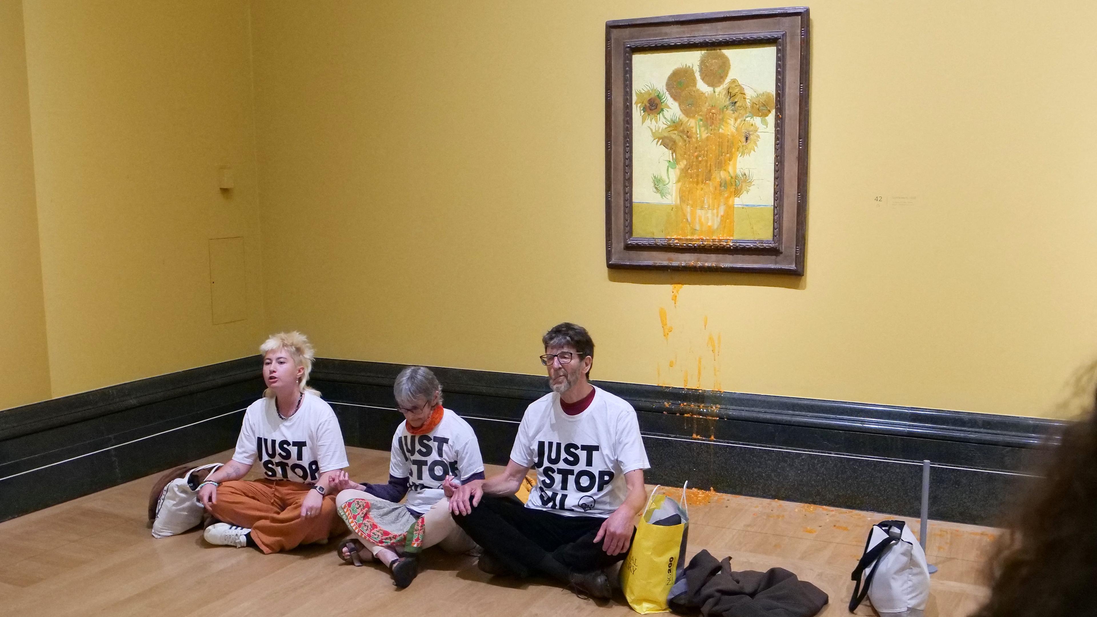 A handout picture from the Just Stop Oil climate campaign group shows three activists sitting on the floor under Vincent van Gogh's "Sunflowers"