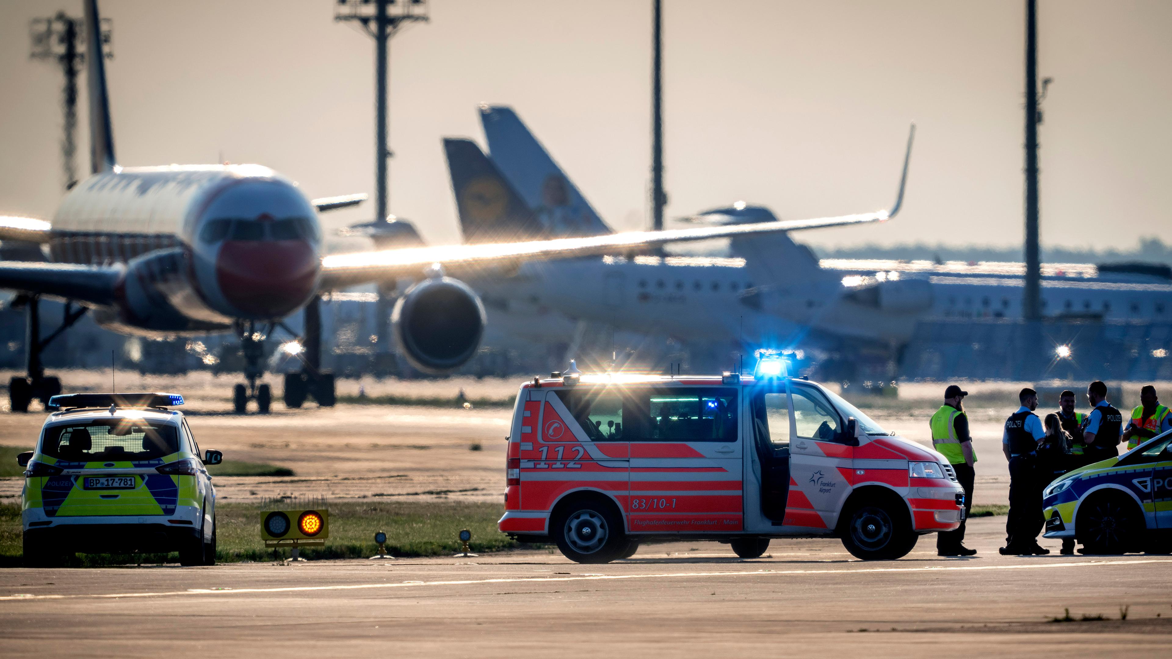 Einsatzfahrzeuge von Polizei, Feuerwehr und Flughafen-Sicherheit stehen auf dem Vorfeld des Frankfurter Flughafens, wo sich zwei Aktivisten festgeklebt haben. 