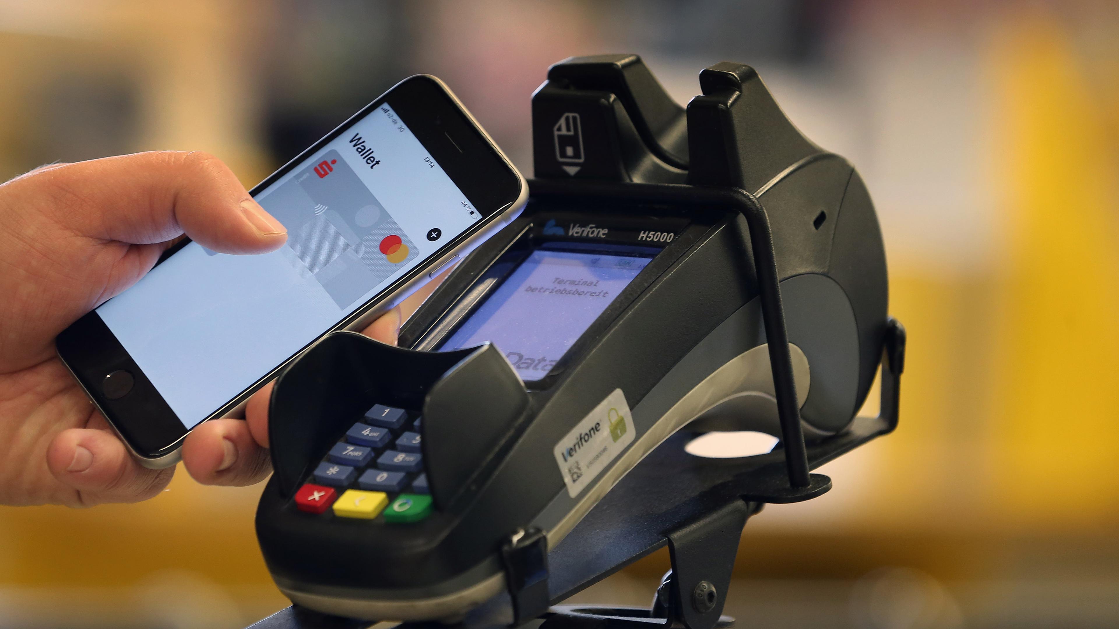 Bayern, Kaufbeuren: Ein Smartphone wird an den Bezahlterminal an der Kasse eines Supermarktes gehalten.