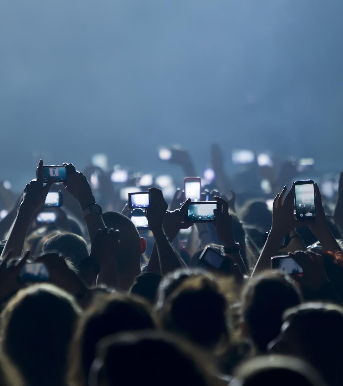 Menschen machen bei einem Konzert Bilder mit dem Smartphone