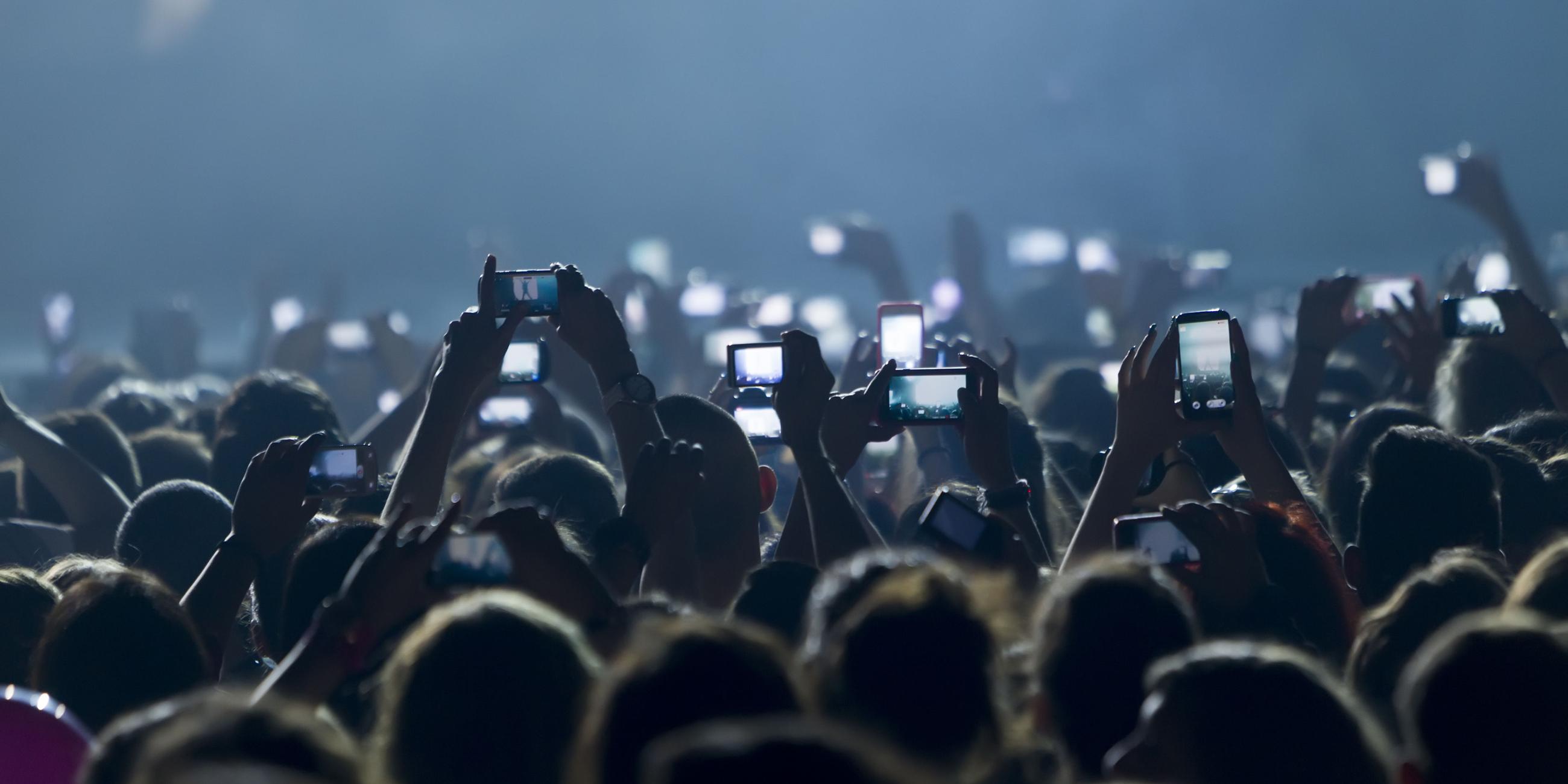 Menschen machen bei einem Konzert Bilder mit dem Smartphone