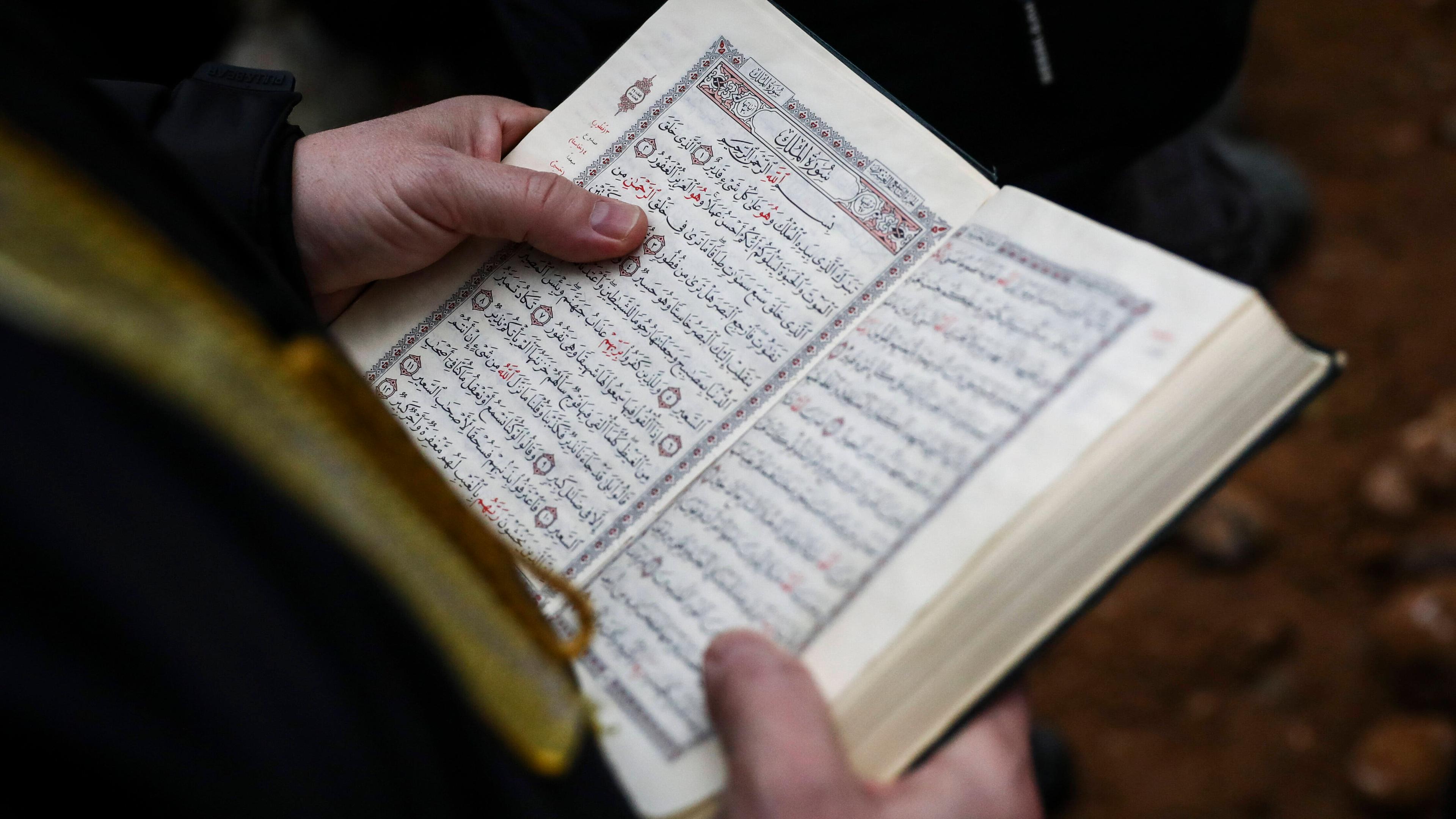 Hand fährt über Zeilen des Koran