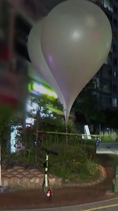 Ballons, beladen mit Unrat vor Häusern einer koreanischen Stadt