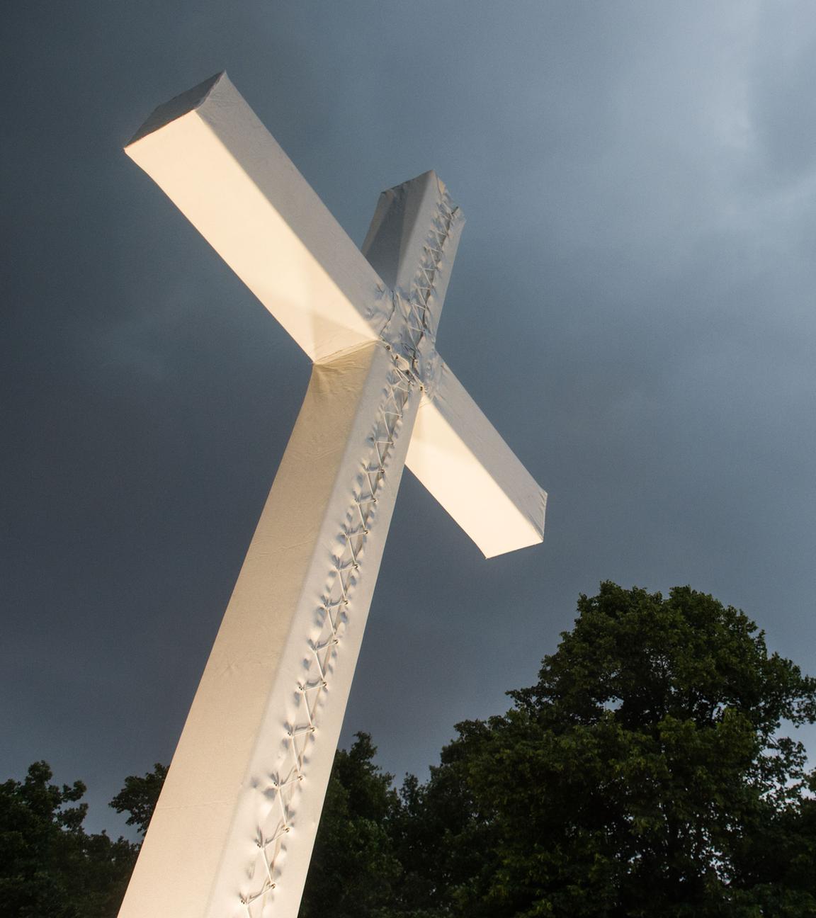 Berlin: Dunkle Wolken ziehen über einem überdimensionierten Kreuz auf.