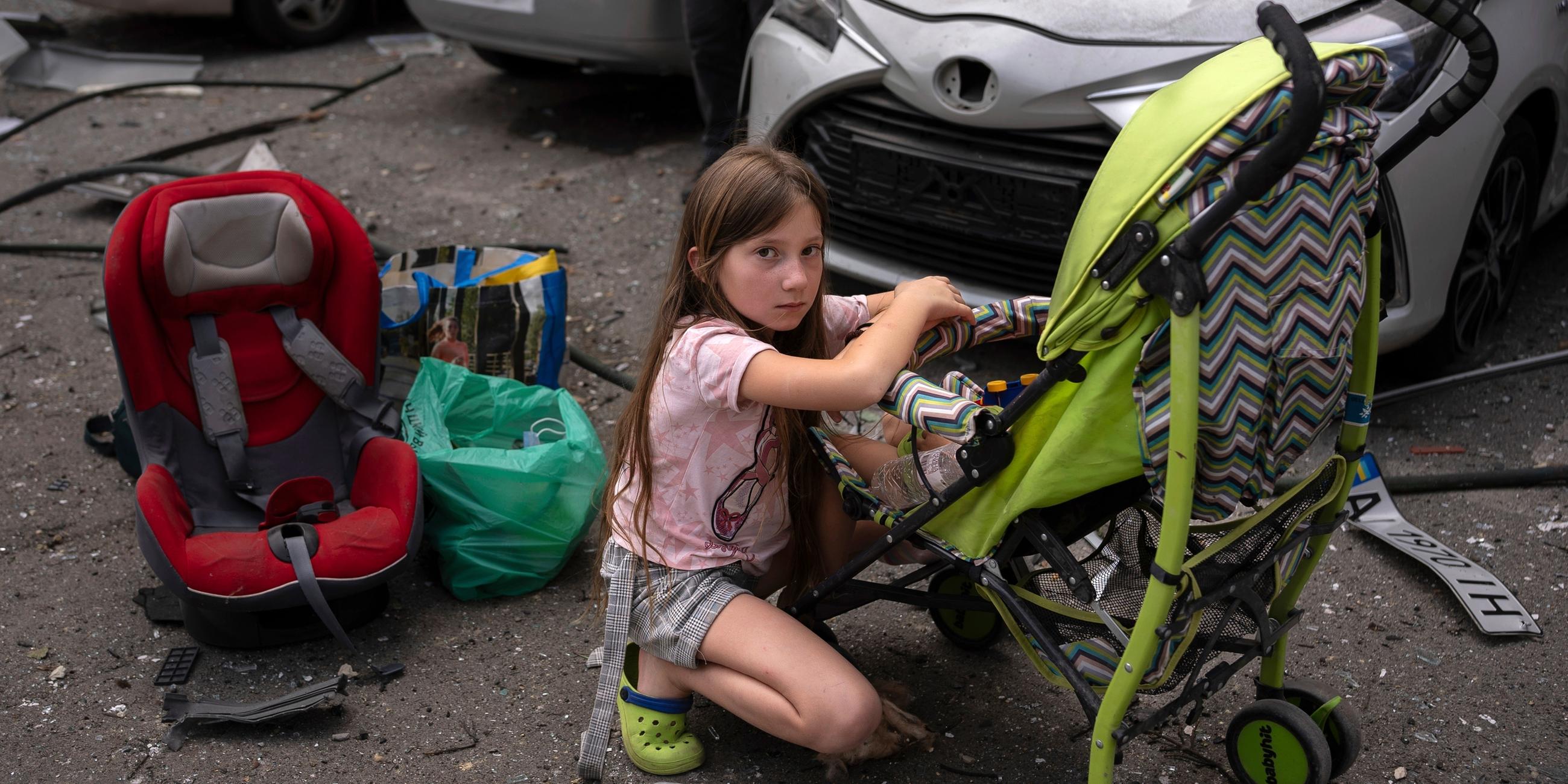 Polina, 10, kümmert sich um ihre Schwester Marina, 3, an der Stelle des von russischen Raketen getroffenen Kinderkrankenhauses Okhmatdyt in Kiew (Ukraine)