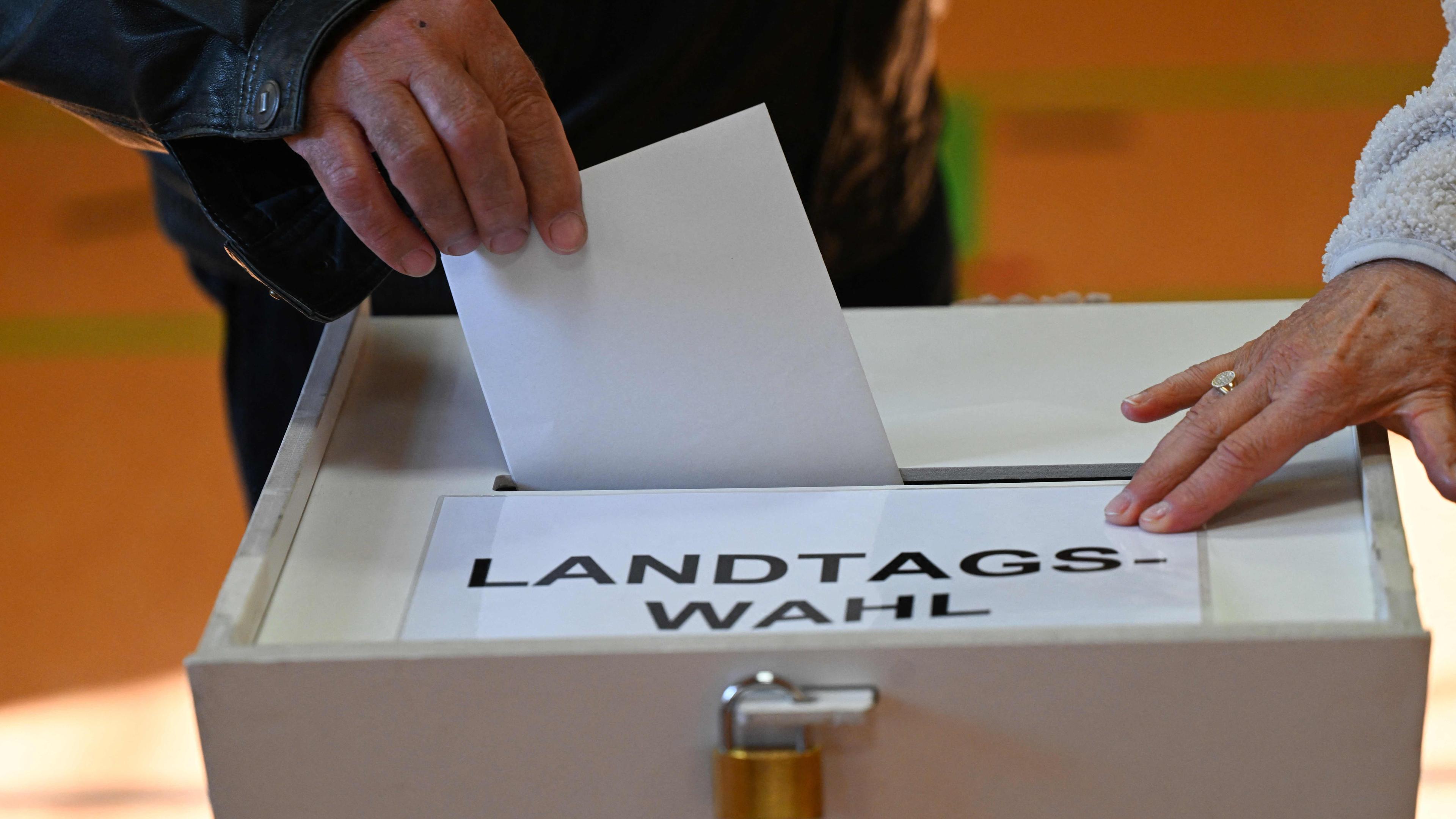 Ein Wähler gibt bei der Landtagswahl in Brandenburg seinen Stimmzettel in die Wahlurne ab.