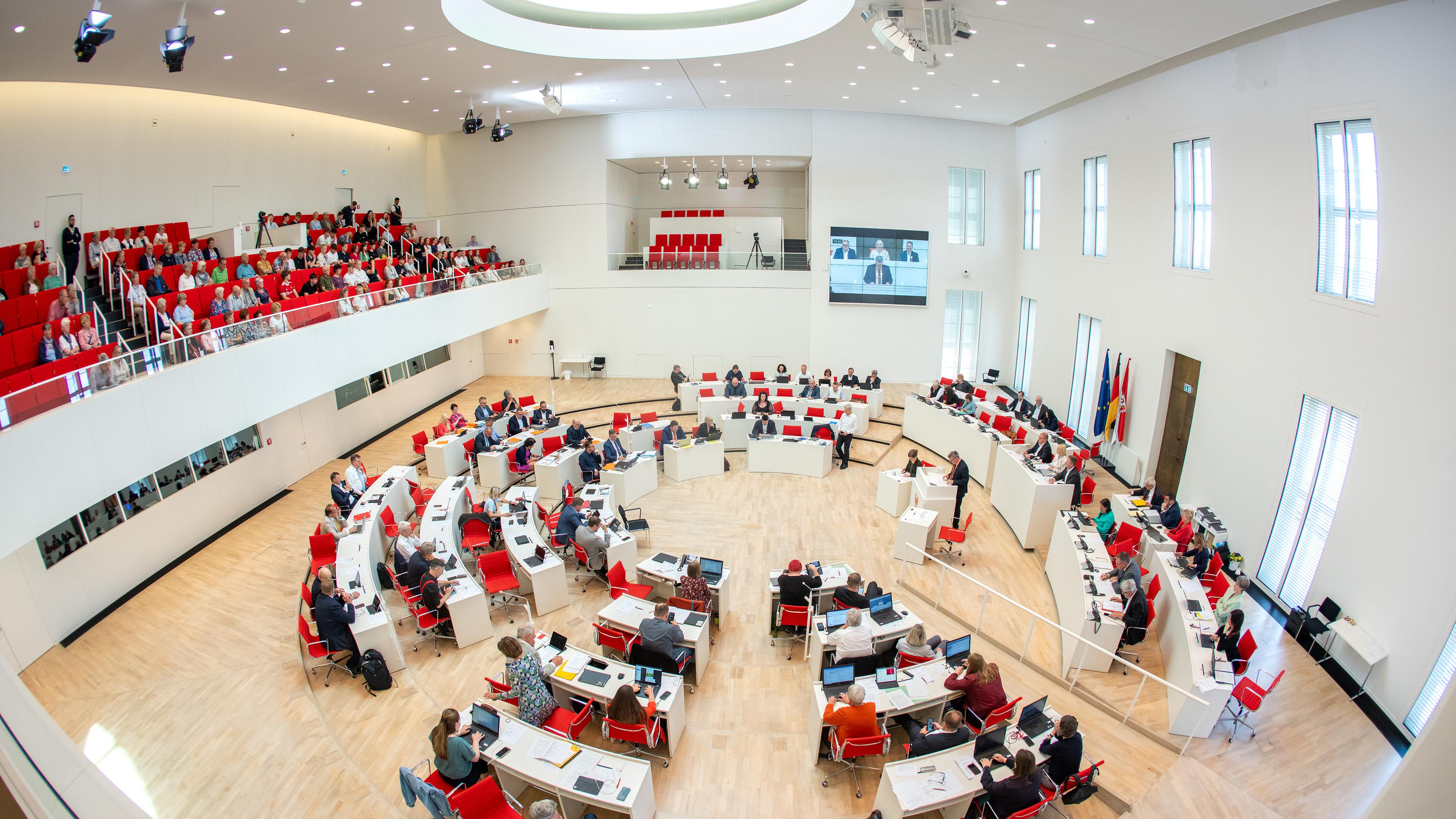 Abgeordnete und Besucher auf der Tribüne verfolgen eine Debatte im Landtag von Brandenburg.