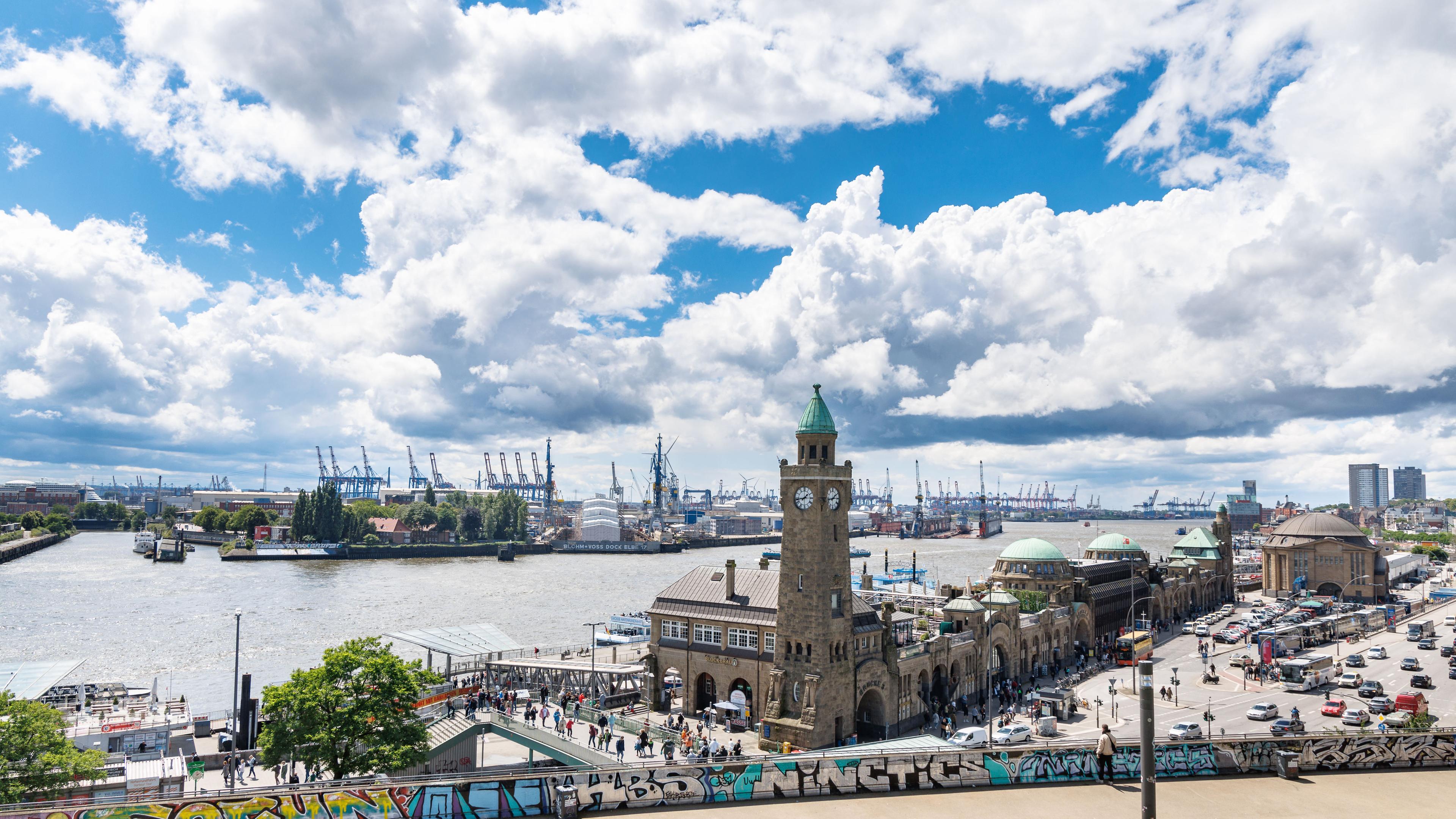 Wolken sind über den Landungsbrücken und dem Hamburger Hafen zu sehen.