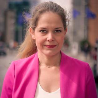 Eine Frau mit braunen Haaren lächelt in die Kamera.