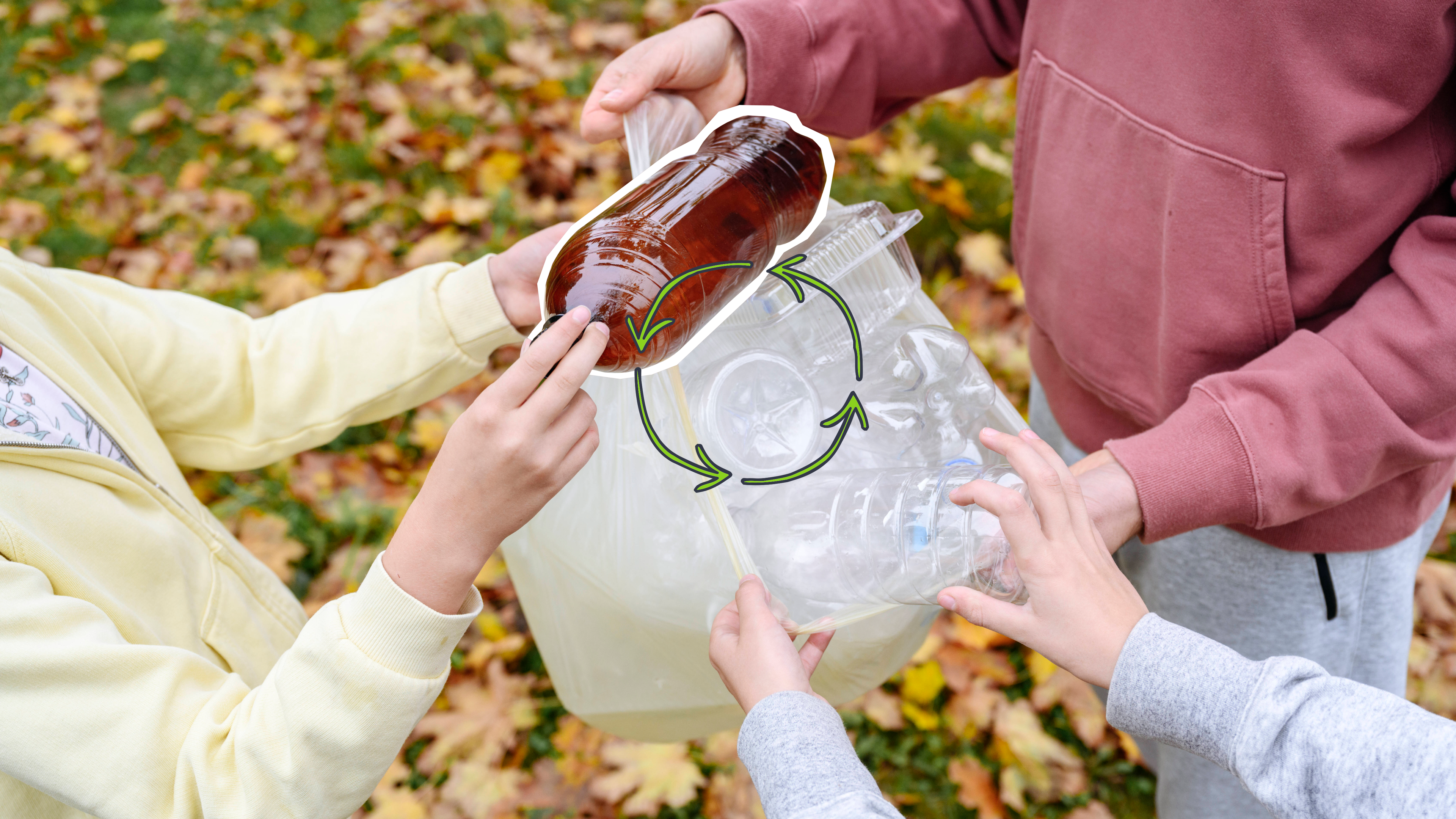 Drei Kinder halten einen Müllbeutel mit Plastikflasche in den Händen. Ein Kind legt eine braune Plastikflasche in den Müllbeutel.