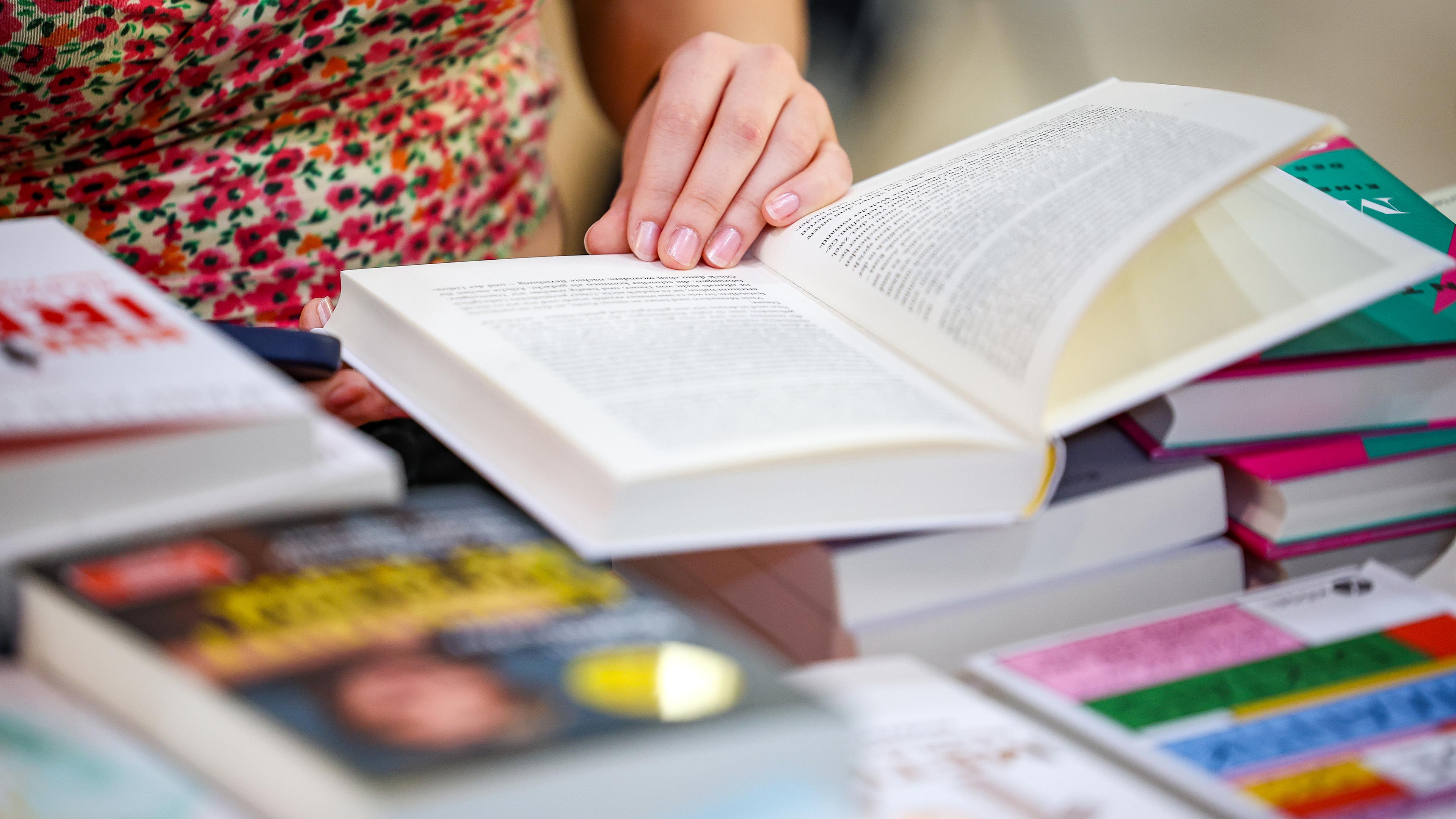 Sachsen, Leipzig: Eine Besucherin liest in einem Buch auf der Leipziger Buchmesse.