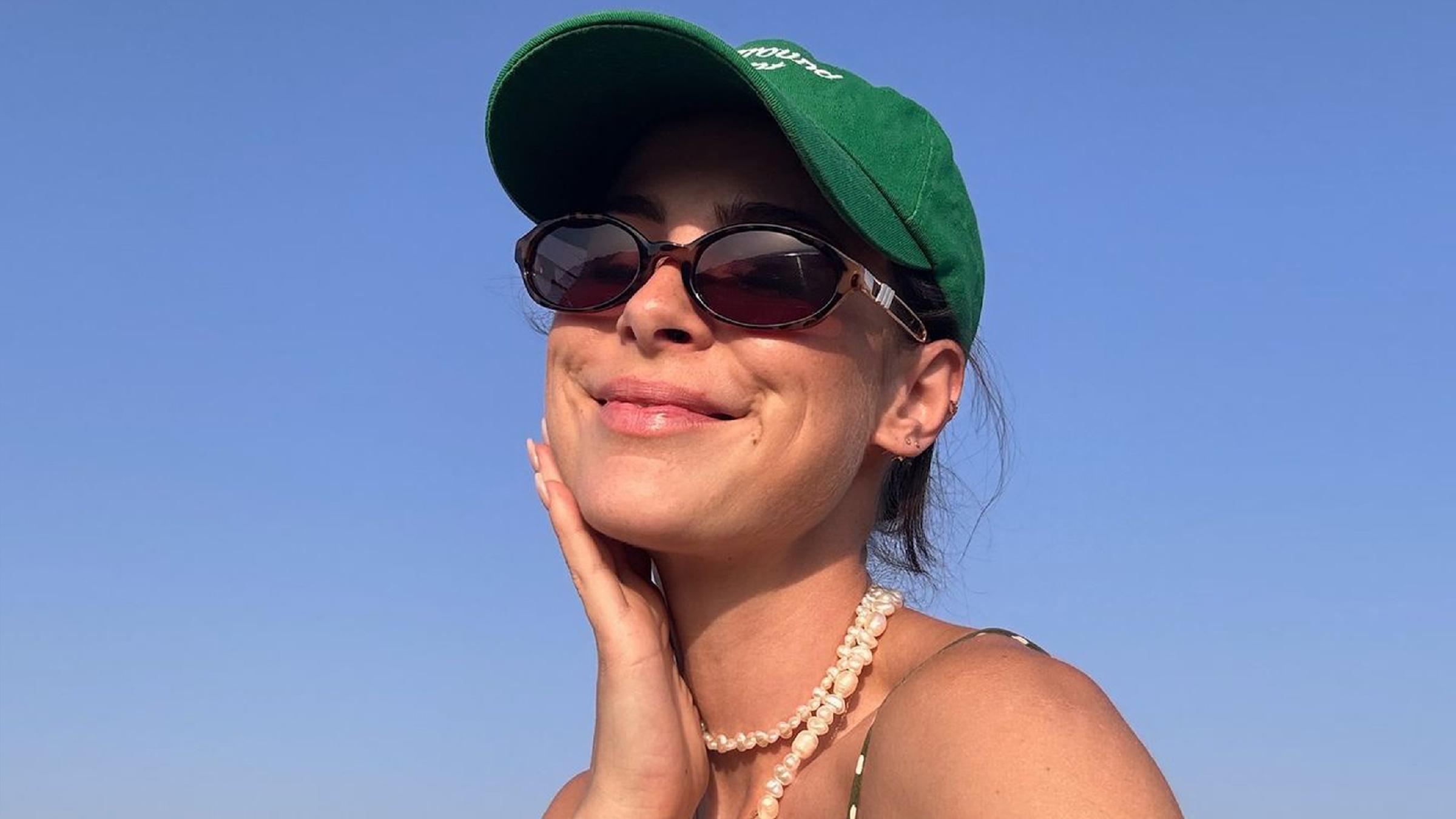 Die Sängerin Lena Meyer-Landrut lächelnd mit Kappe und Sonnebrille.