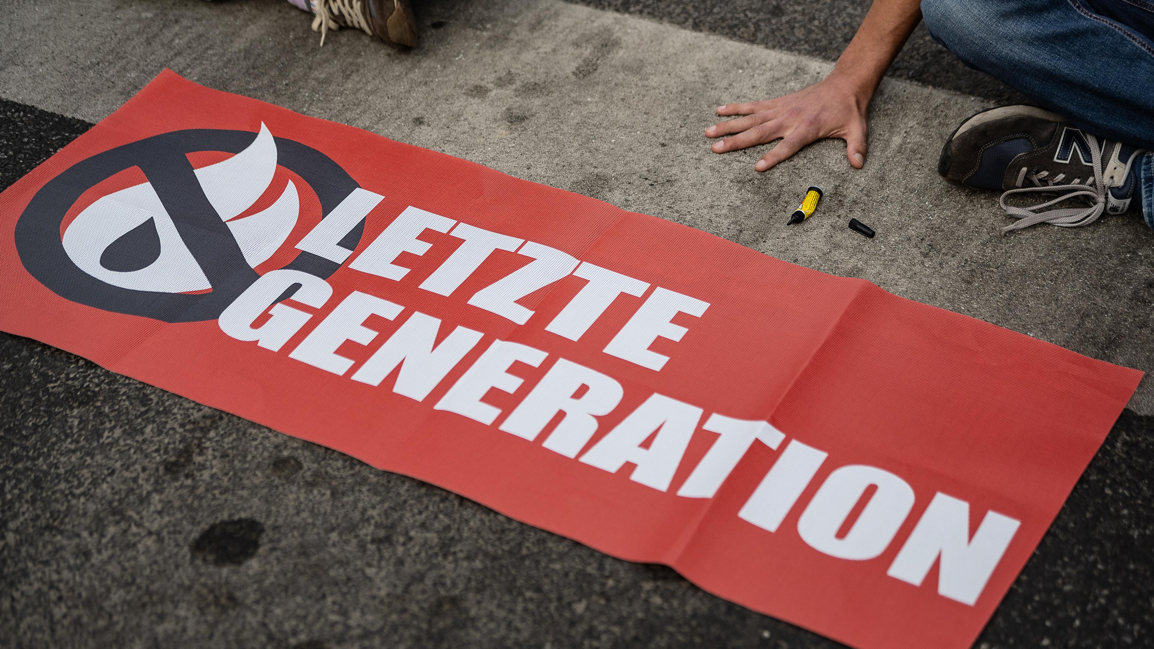 Niedersachsen, Göttingen: Ein Aktivist der Gruppe "Letzte Generation", der seine Hand selbst auf der Straße festgeklebt hat, blockiert eine Kreuzung am Geismar Tor. Archivbild
