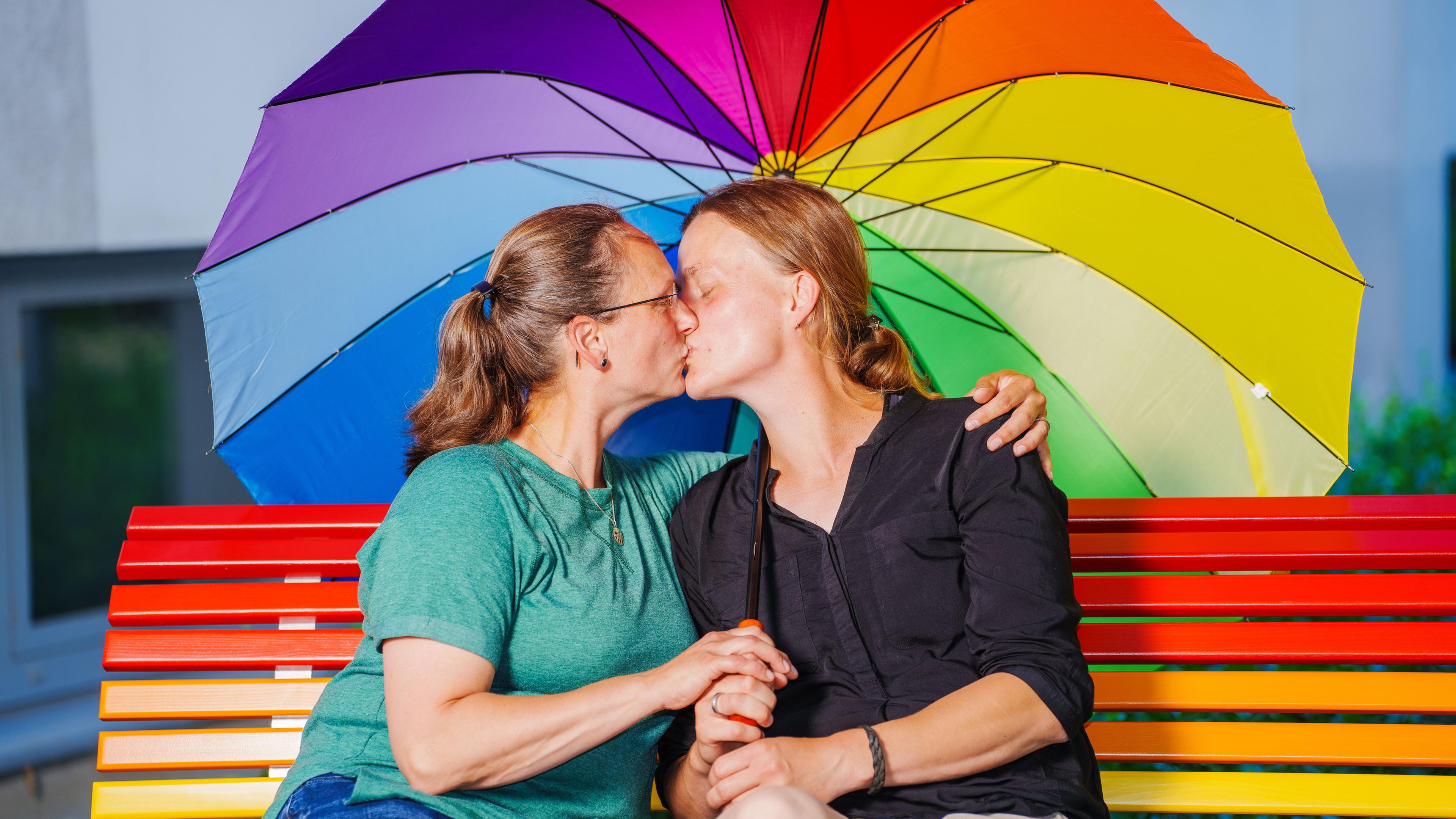 Rheinland-Pfalz, Mainz: Bettina (l) und Jennifer Leybold, Donnersbergkreis, sitzen zusammen auf der Regenbogen-Bank.