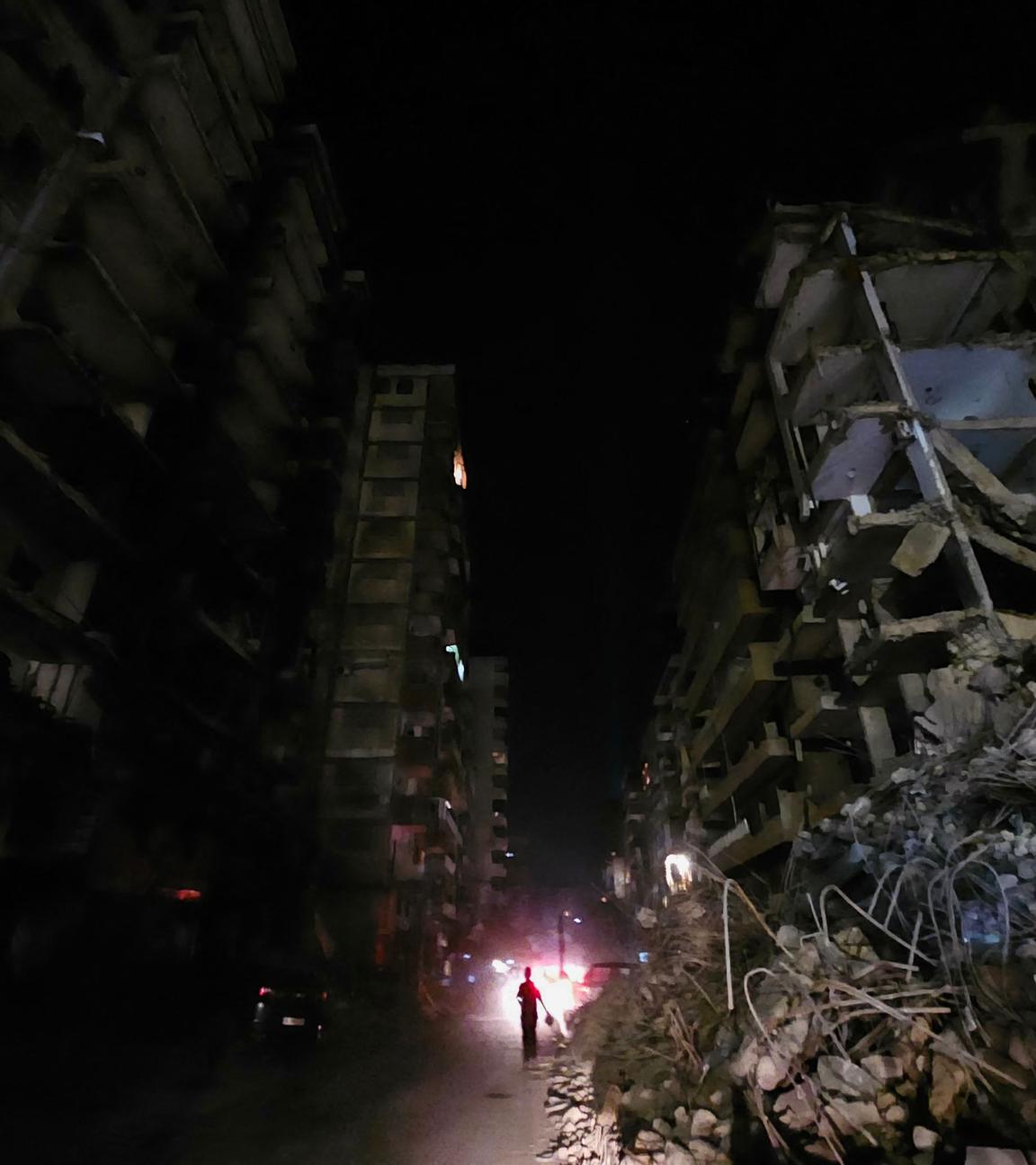 People walk in the dark amid destruction in the Beirut southern suburbs neighbourhood of Haret Hreik