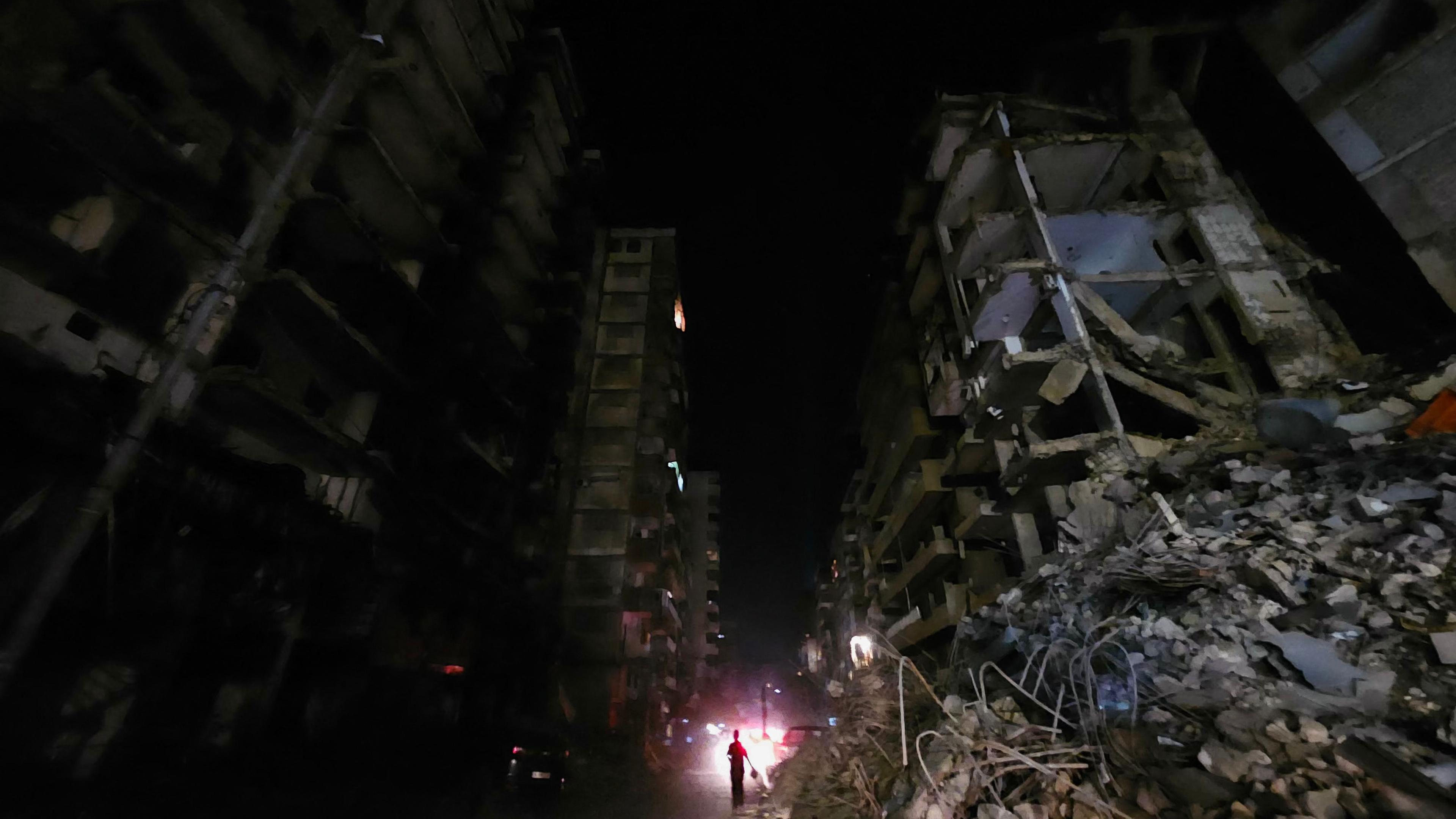 People walk in the dark amid destruction in the Beirut southern suburbs neighbourhood of Haret Hreik