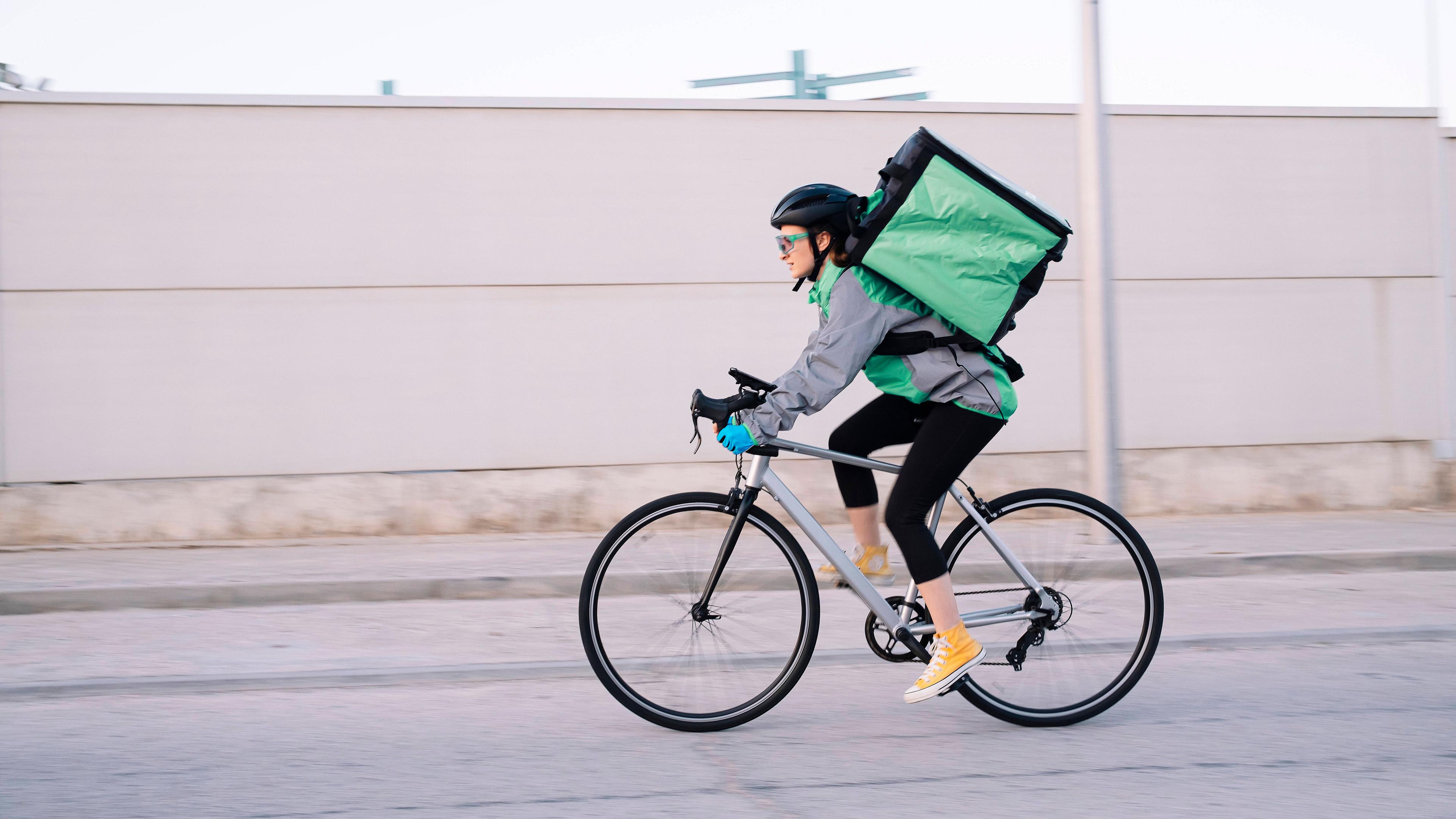 Eine Fahrradkurierin fährt eine Straße entlang.