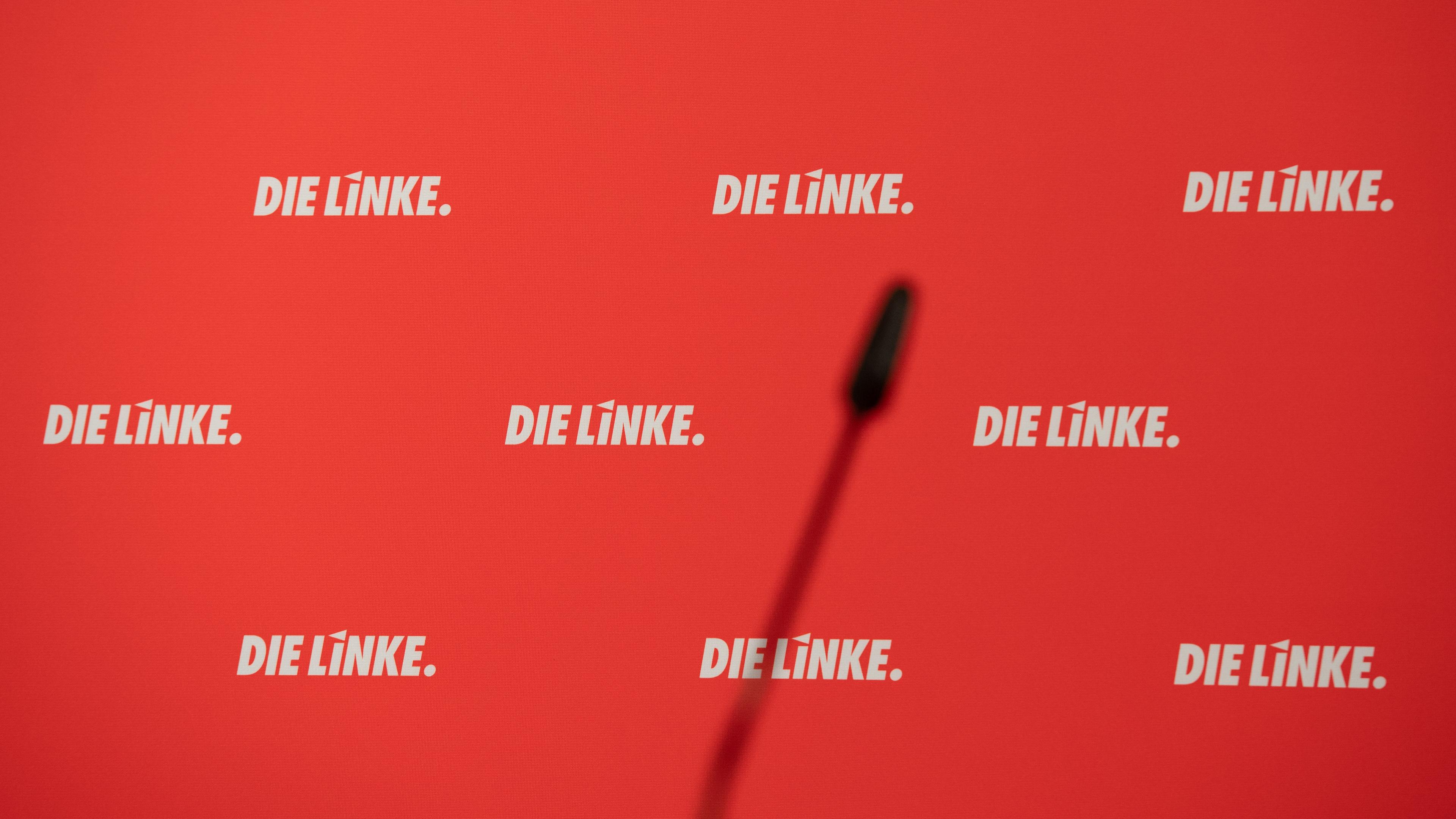 Das Parteilogo "Die Linke" steht auf einer Stellwand hinter einem menschenleeren Podium