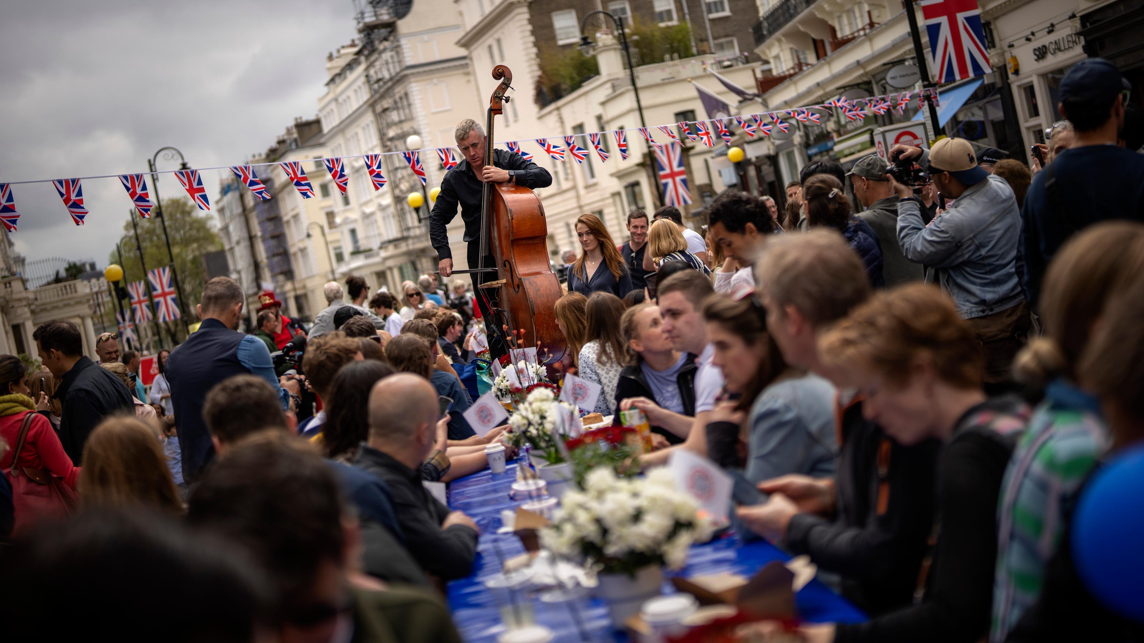 London: Musiker spielen während Menschen an langen Tischen das sogenannte "Big Lunch" feiern.