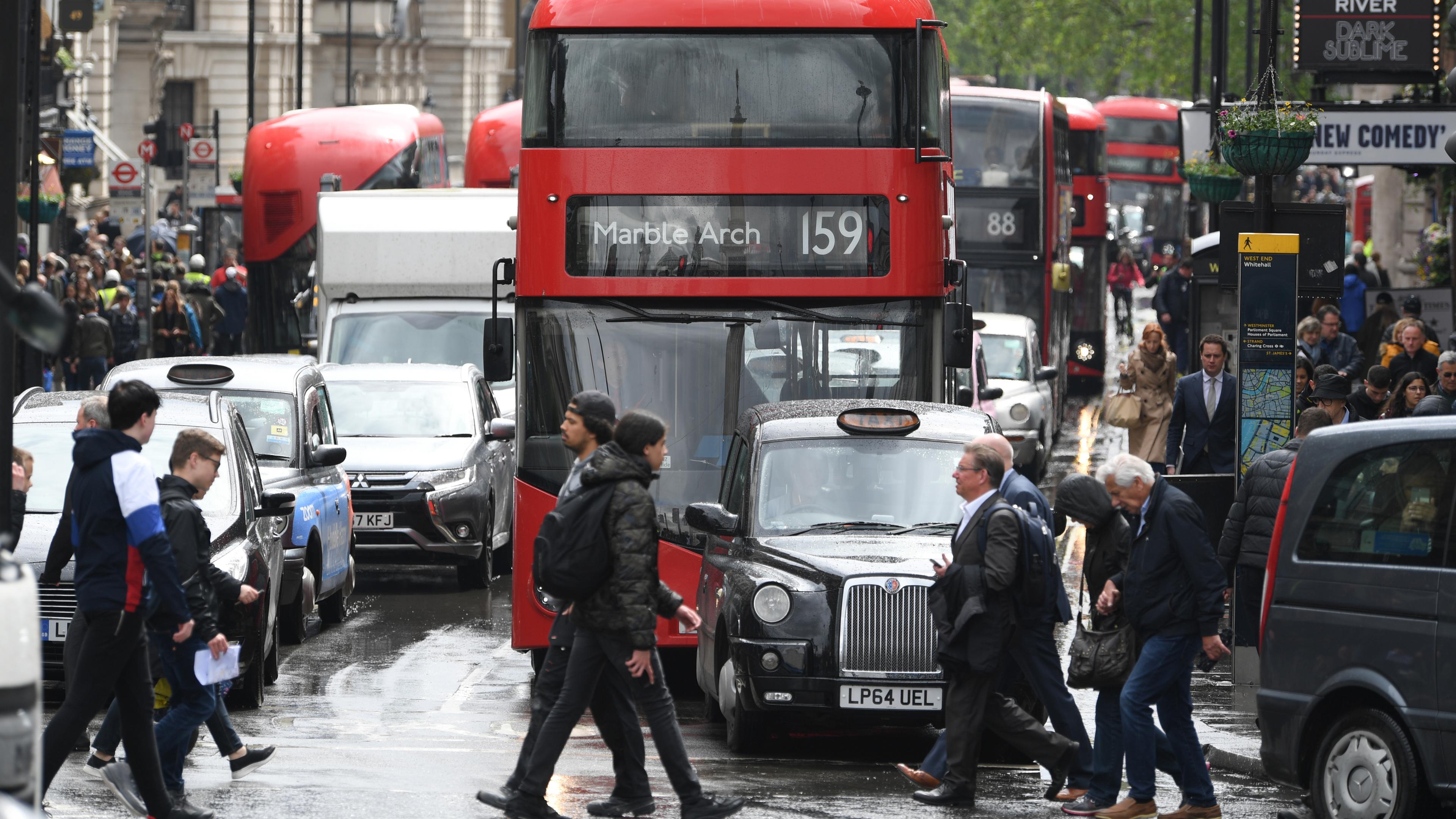 Fußgänger laufen über eine vielbefahrene Straße in London.