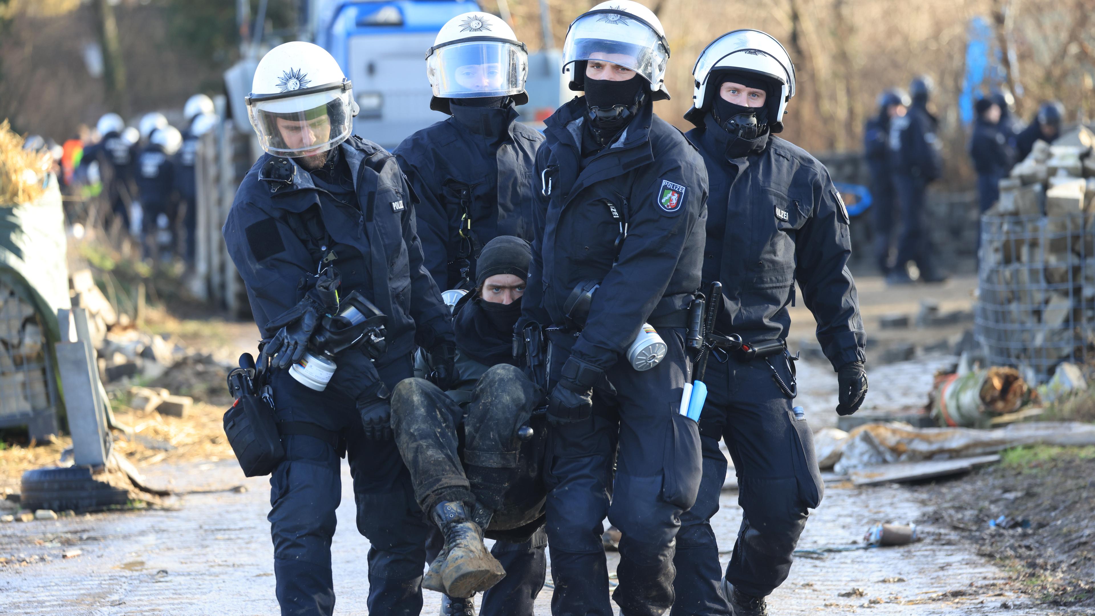 Vier Polizisten tragen einen Klimaaktivisten weg