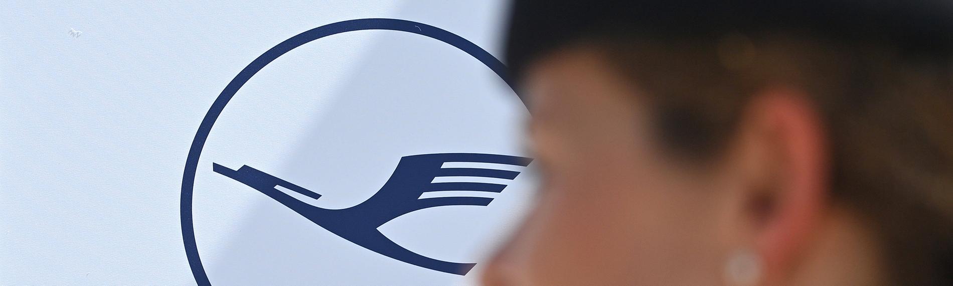 Flugbegleiterin der Lufthansa vor Logo