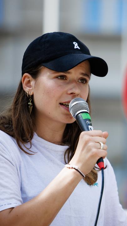 Luisa Neubauer spricht vor einem Schild mit dem durchgestrichenen Wort "Gas".