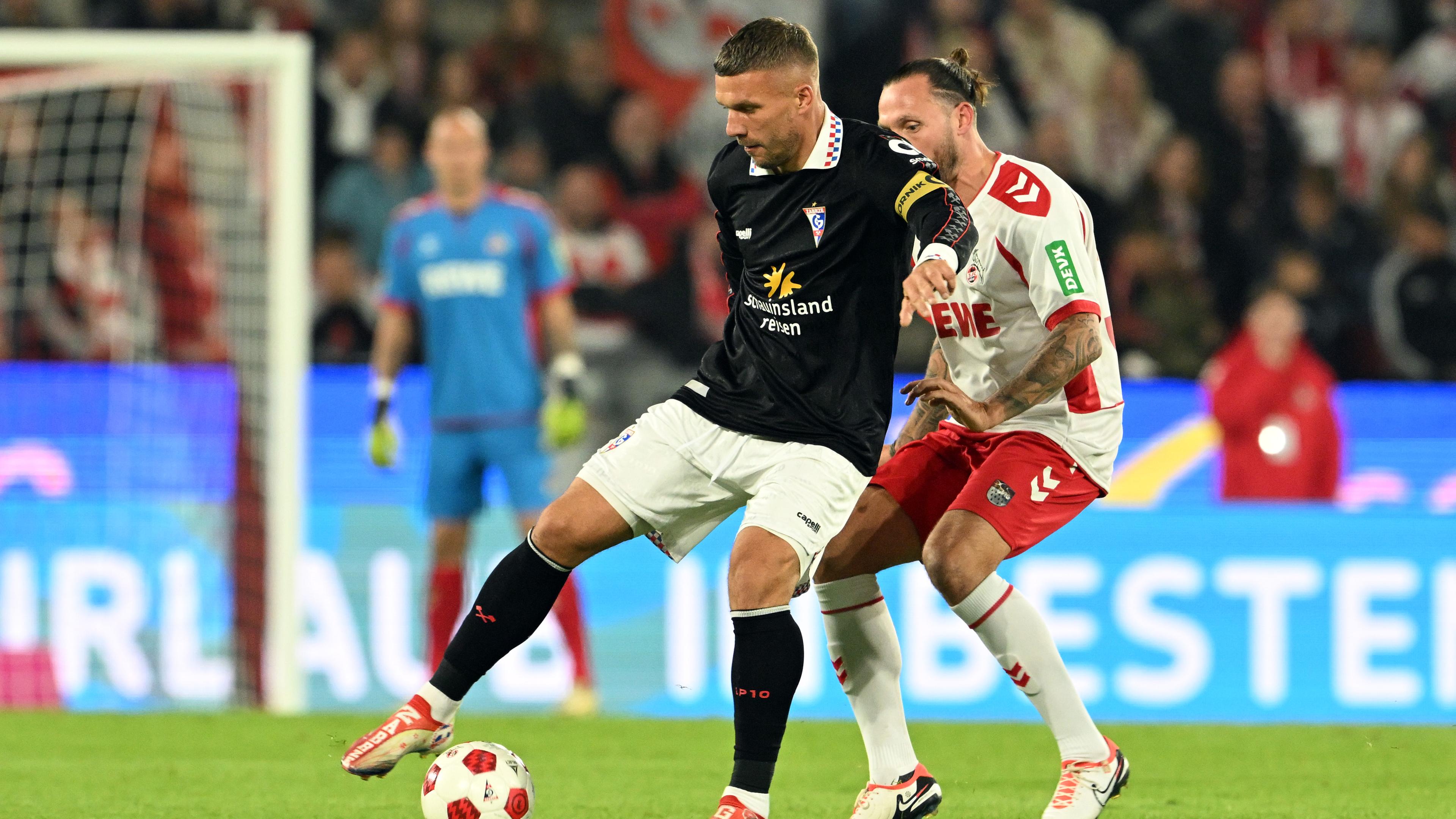 Lukas Podolski (l) von der Poldi 11 und Marco Höger von Köln kämpfen um den Ball. 