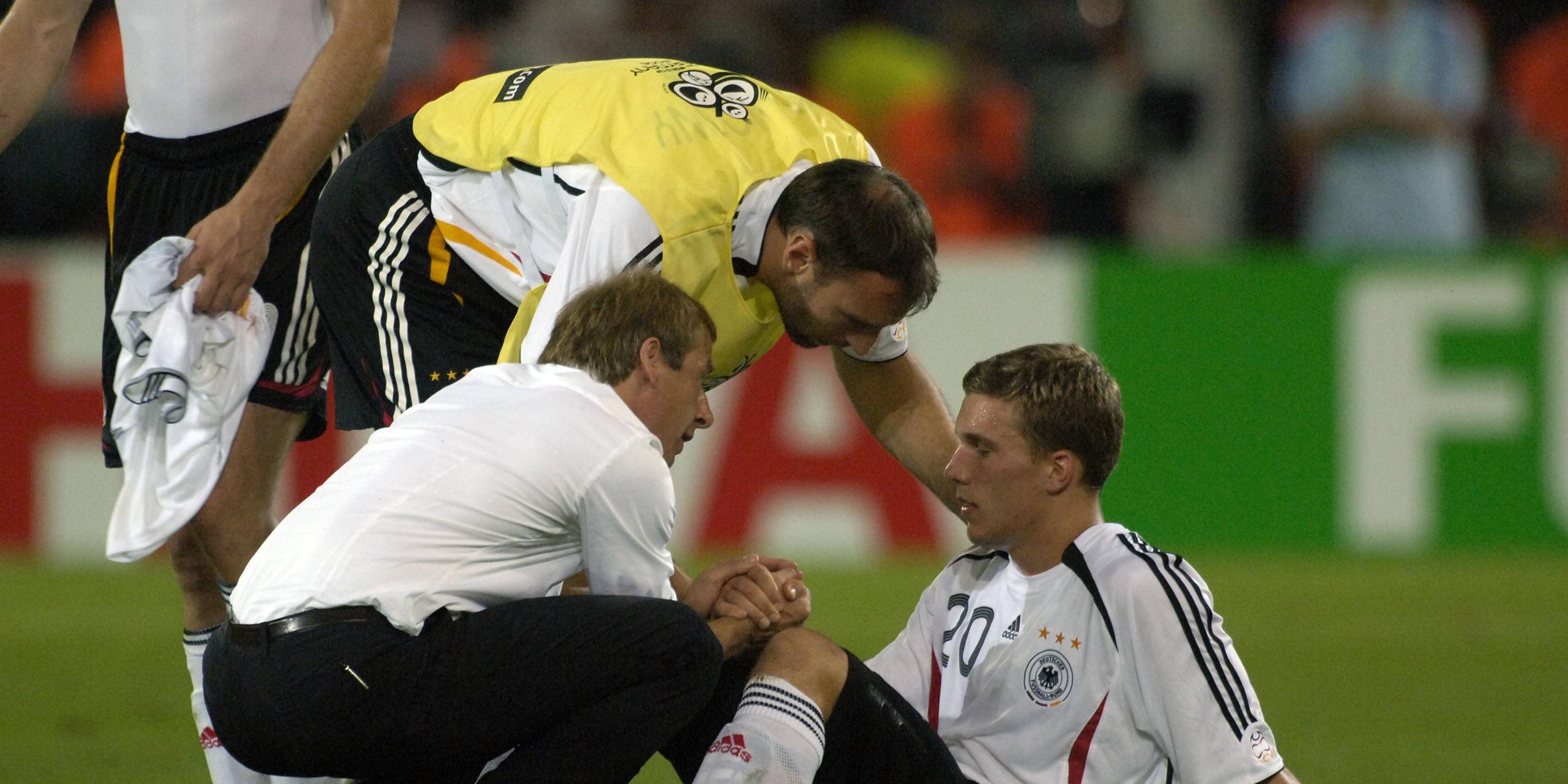 Bundestrainer Jürgen Klinsmann (links) und Jens Nowotny (Mitte) trösten den enttäuschten Lukas Podolski (rechts)