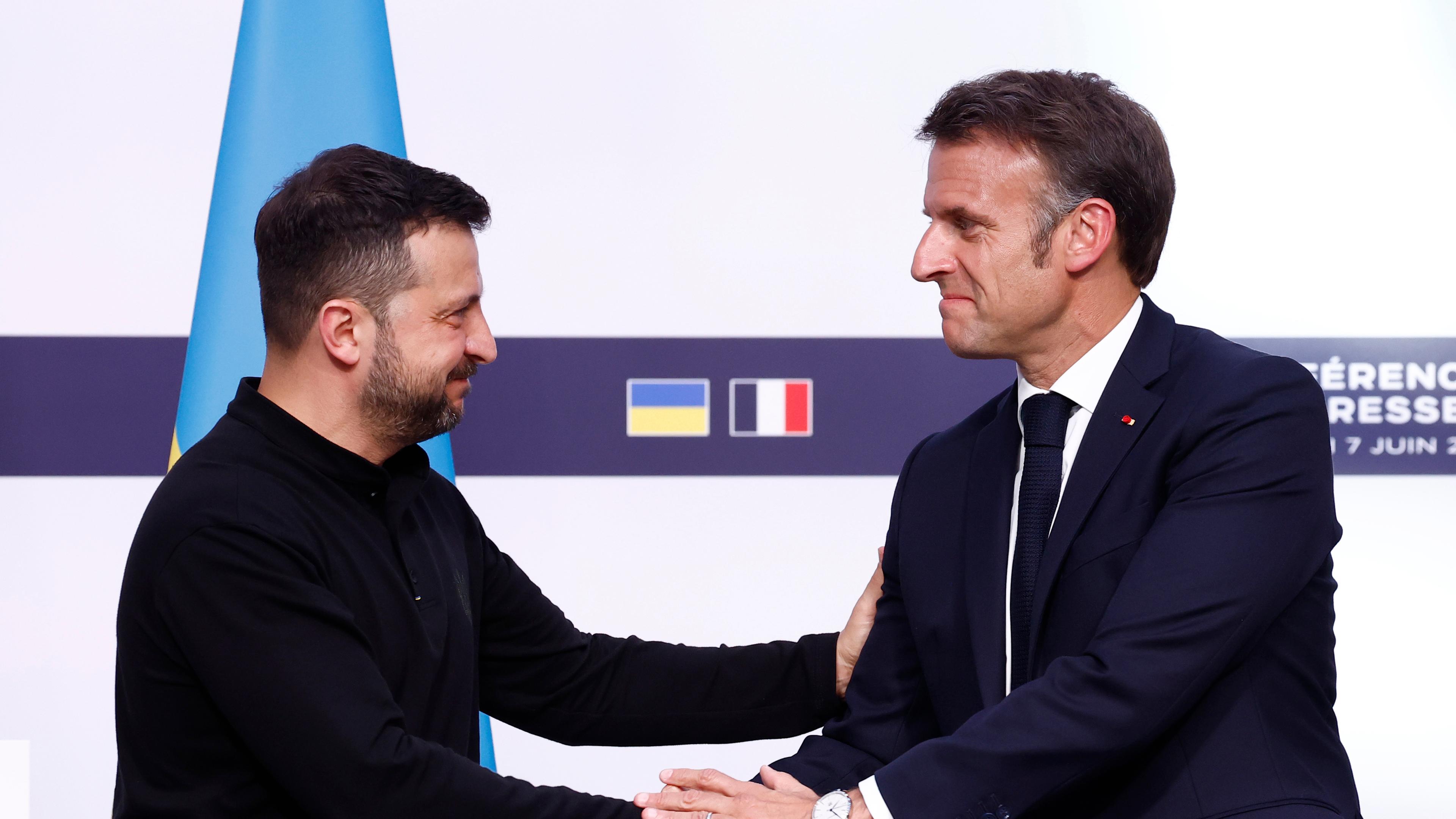 Der ukrainische Präsident Wolodymyr Selenskyj (l) schüttelt dem französischen Präsidenten Emmanuel Macron im Elysee-Palast während einer gemeinsamen Pressekonferenz die Hand. 
