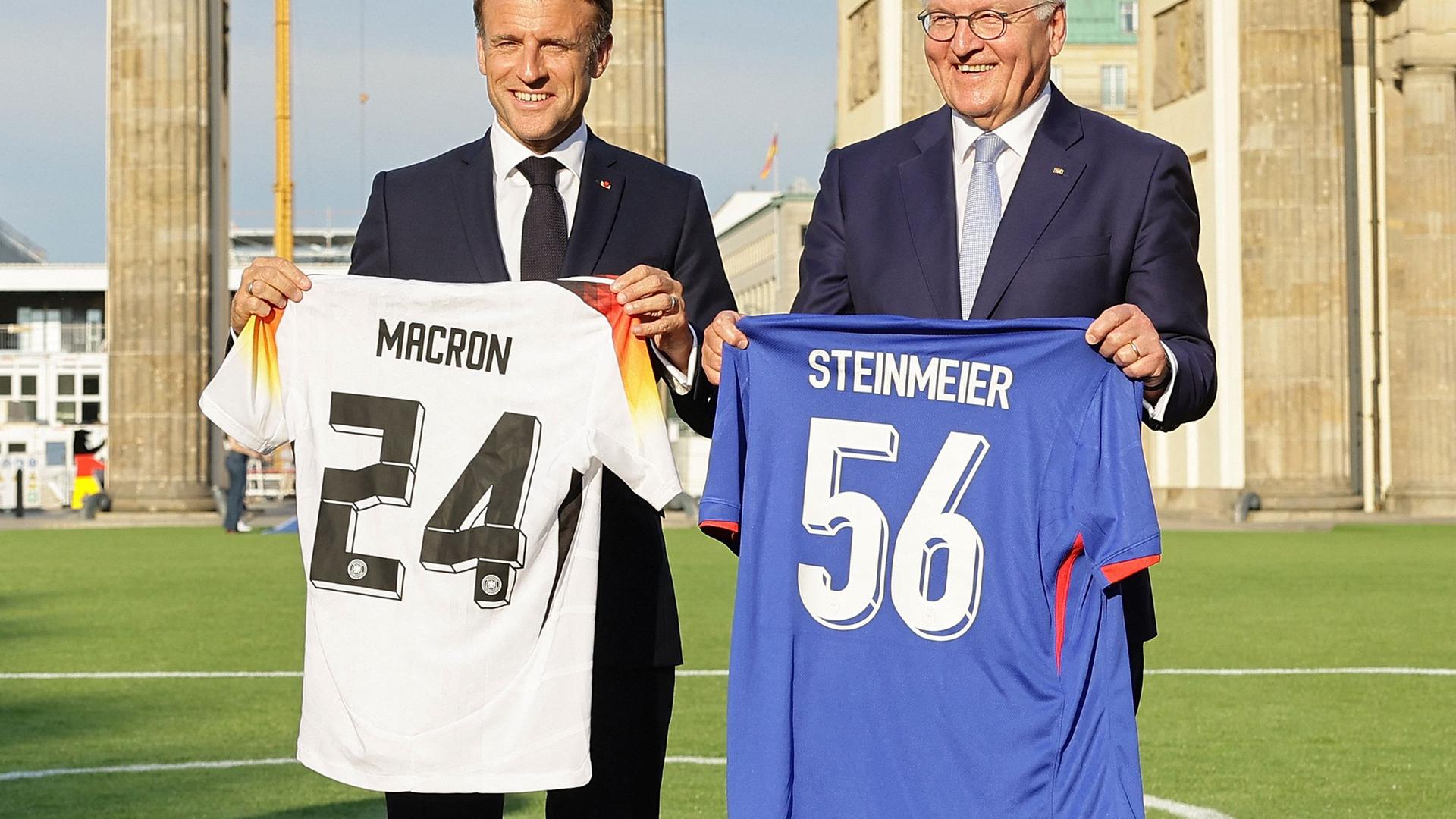 French President Emmanuel Macron and German President Frank-Walter Steinmeier pose with football shirts as they inaugurate the German-French Sports Summer 2024 in Berlin, Germany on May 26, 2024.