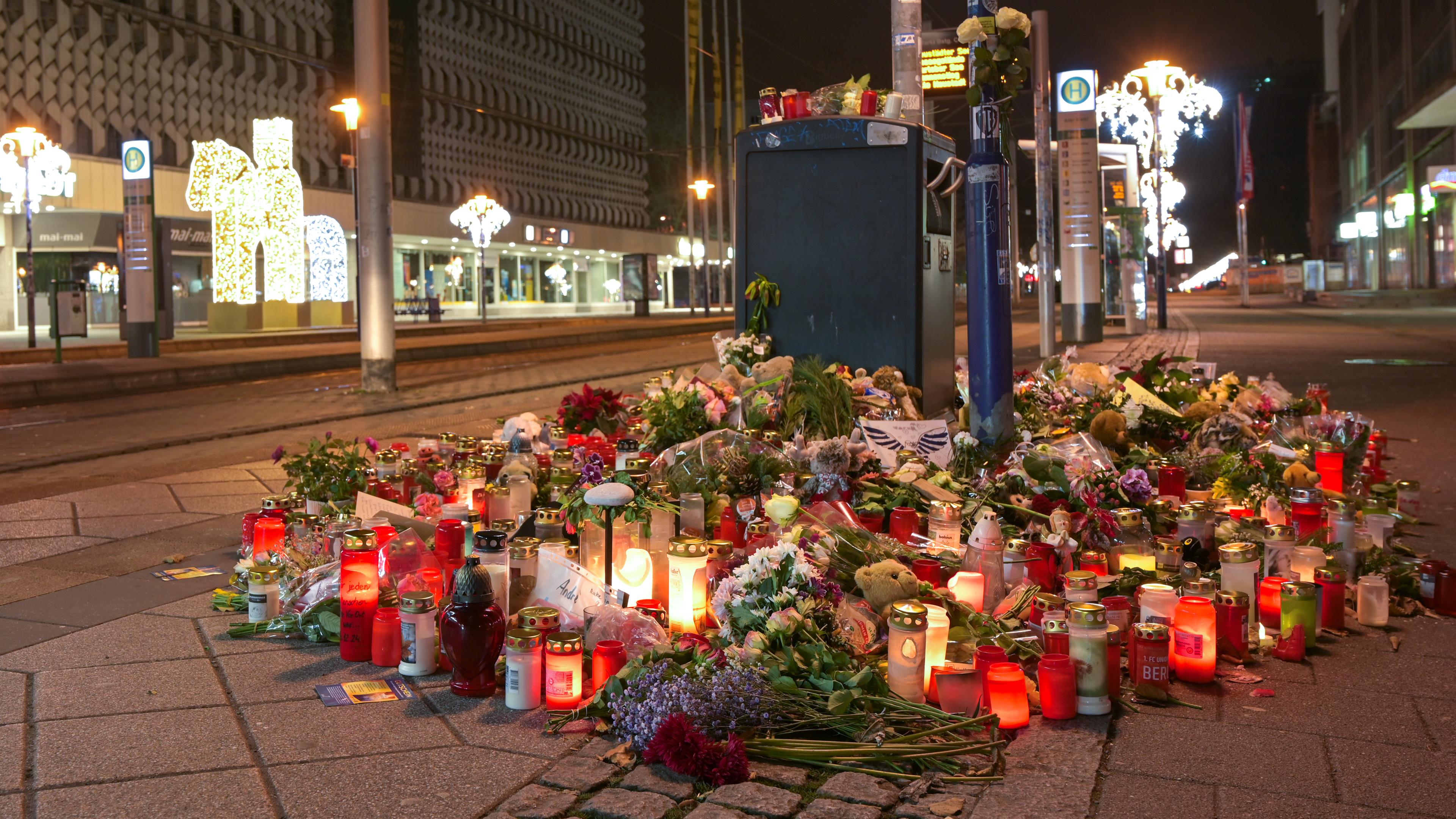 Blumen und Kerzen stehen im Gedenken an die Anschlagsopfer an einer Straßenbahnhaltestelle in der Ernst-Reuter-Allee. 