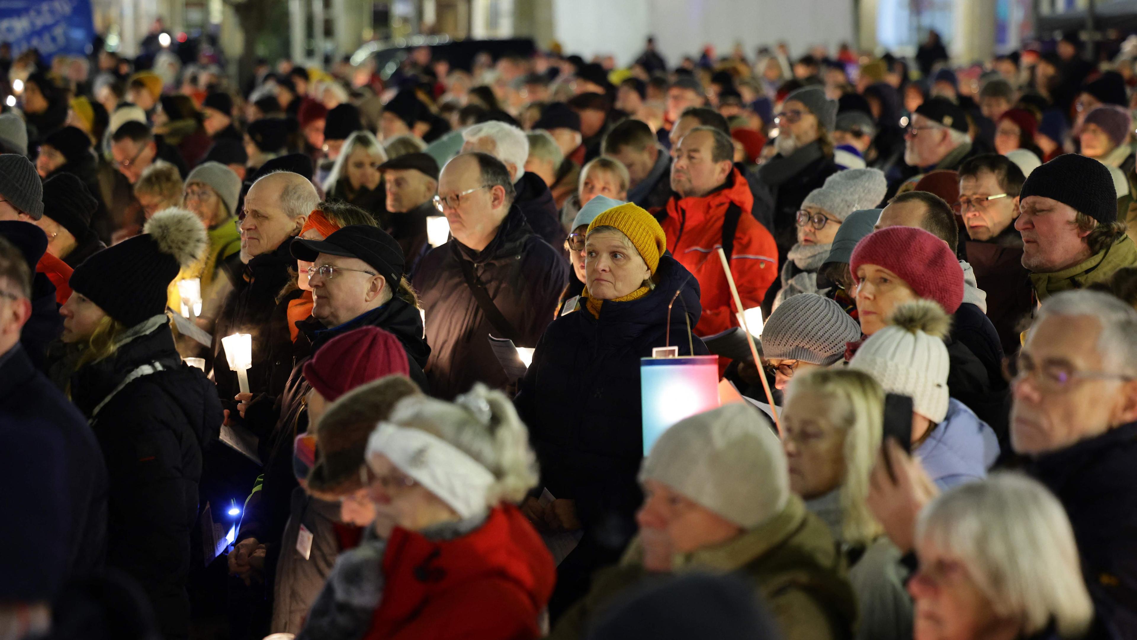 Menschen halten Kerzen und singen bei der Gedenkveranstaltung „Magdeburg singt für eine weltoffene Stadt“ für die Opfer des Weihnachtsmarktanschlags auf dem alten Marktplatz in Magdeburg