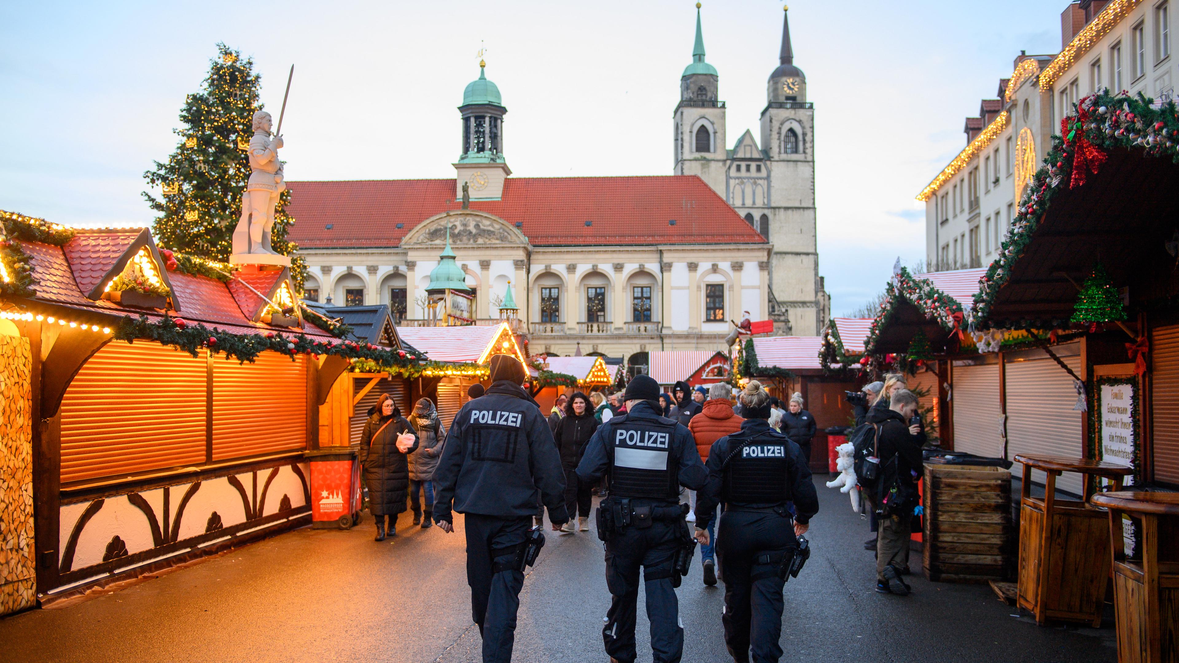 Drei Polizisten gehen über den Magdeburger Weihnachtsmarkt