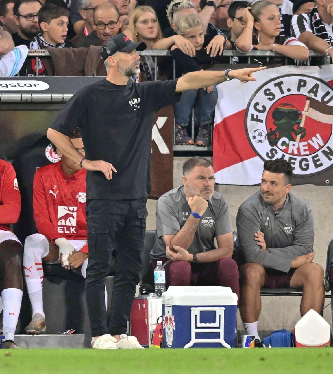 FC St. Pauli - RB Leipzig am 22.09.2024: RB-Trainer Marco Rose deutet Richtung Spielfeld. Im Hintergrund St.-Pauli-Fans auf der Tribüne.