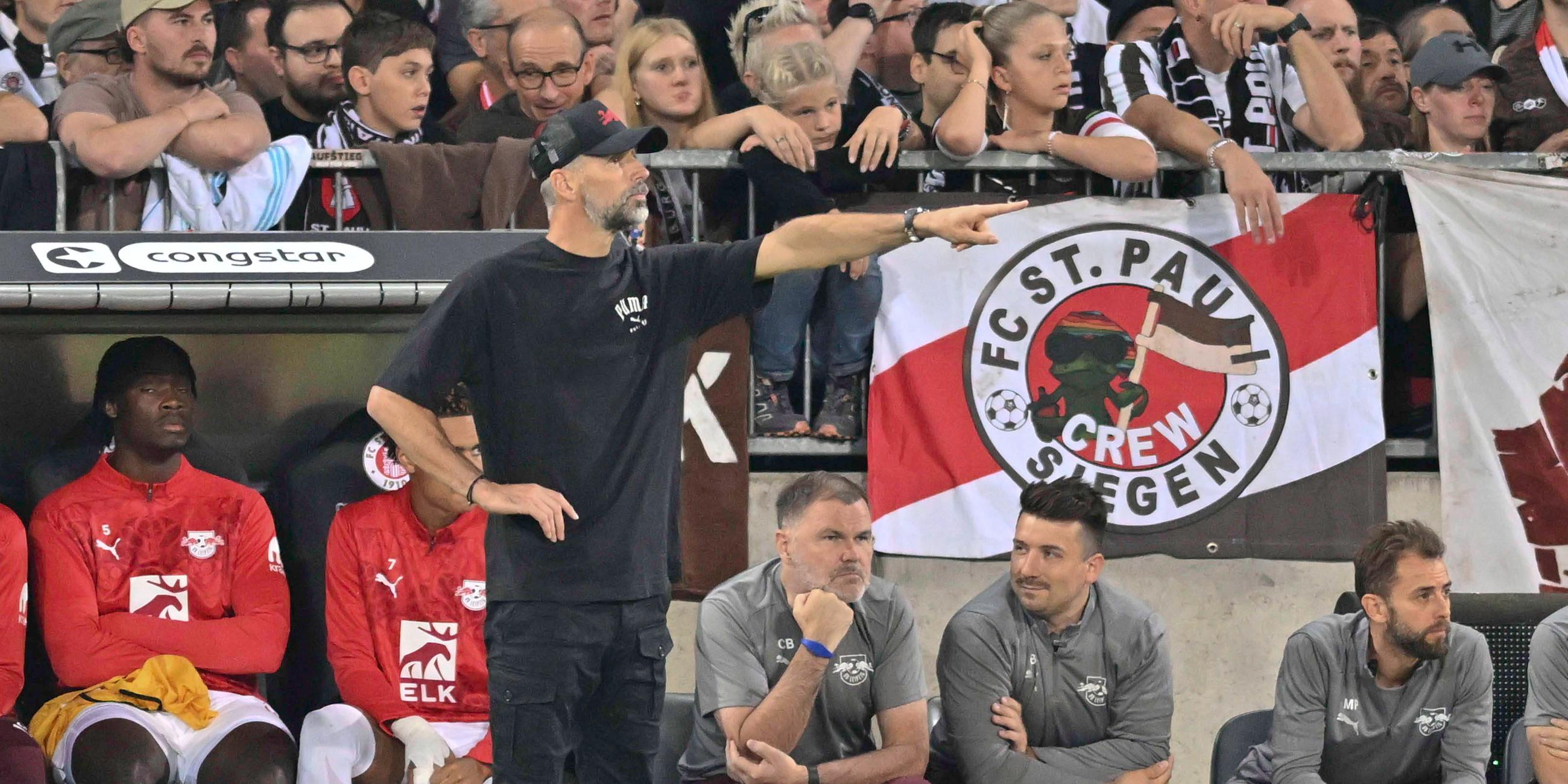 FC St. Pauli - RB Leipzig am 22.09.2024: RB-Trainer Marco Rose deutet Richtung Spielfeld. Im Hintergrund St.-Pauli-Fans auf der Tribüne.